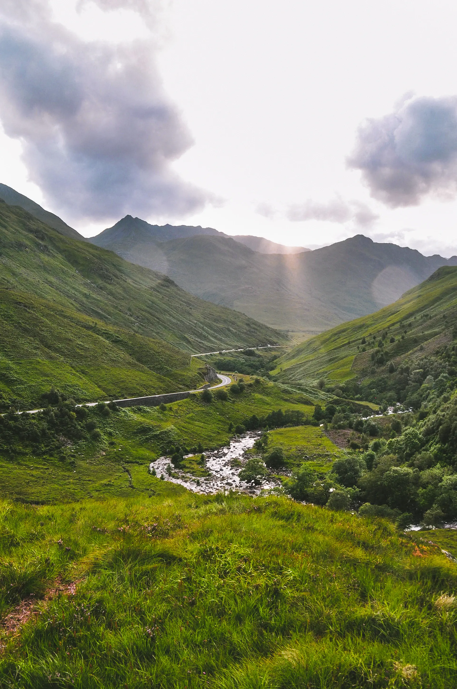 Vast highland valley under low cinematic light, a lone river threading through it