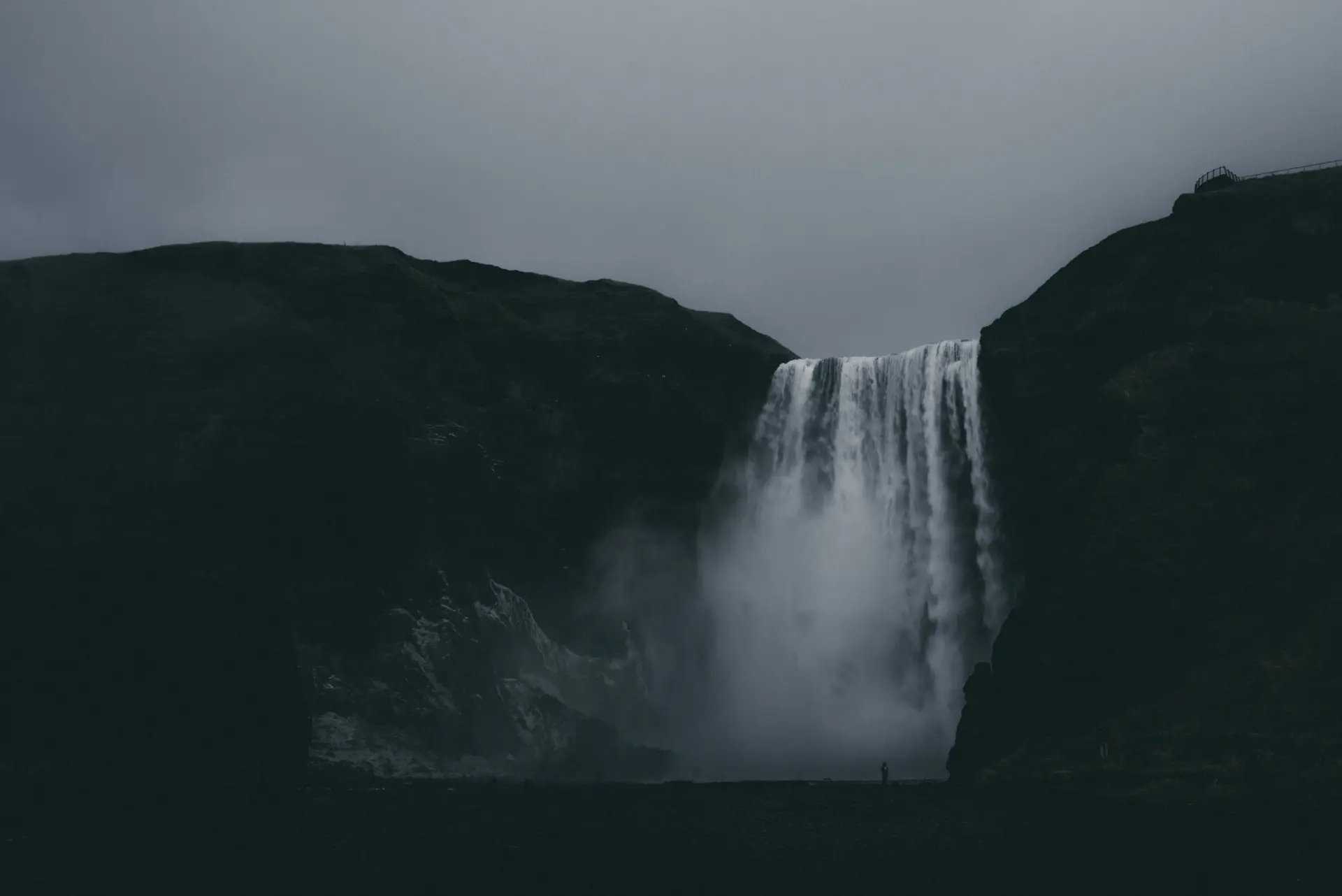 A dark cinematic waterfall plunging into shadowed rock