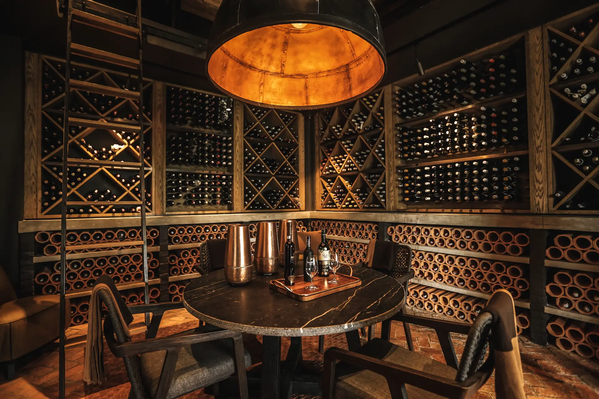 A dramatically lit wall of fine wine and spirits bottles in a private cellar