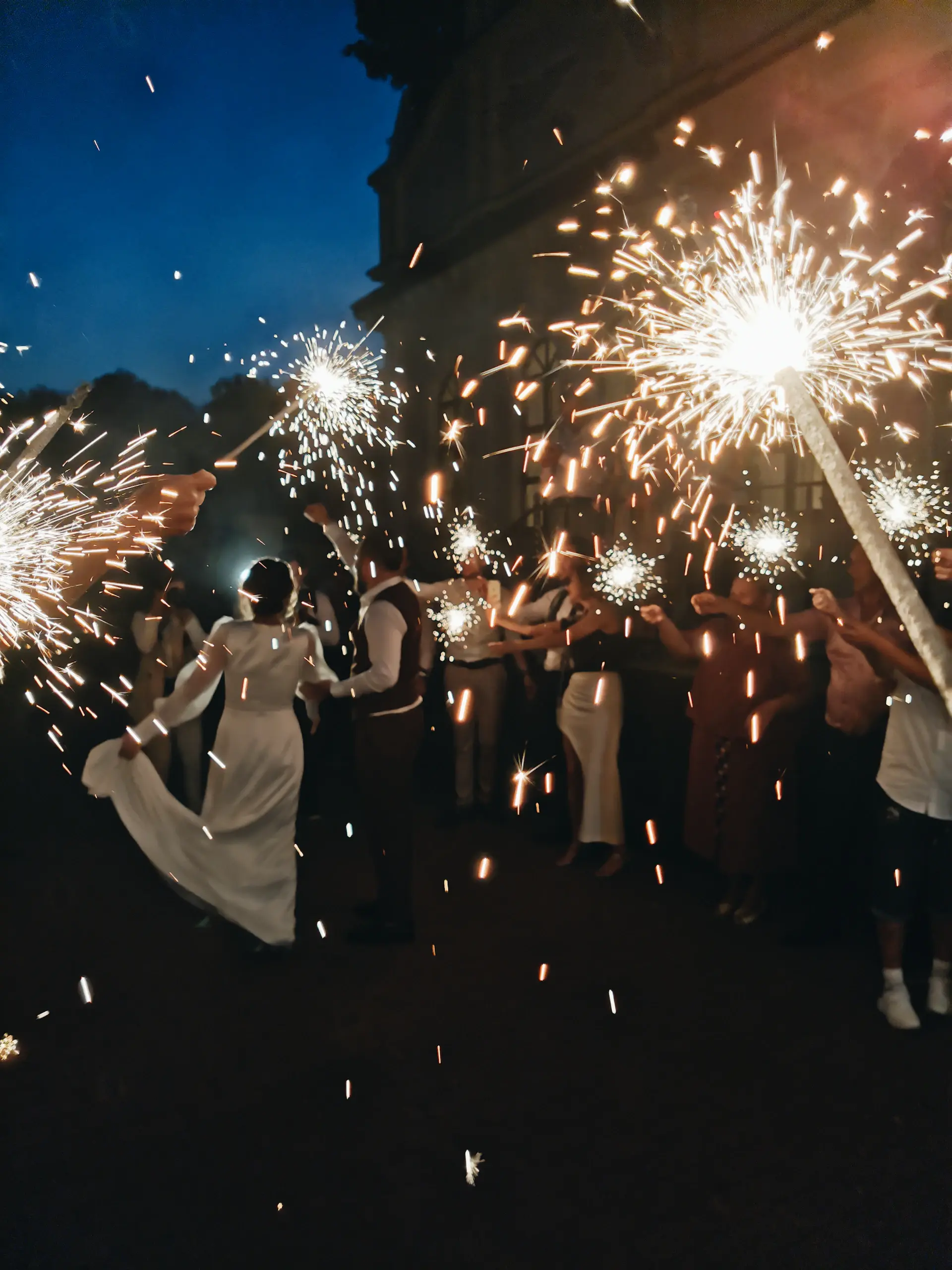 A sparkler send-off for newlyweds outside a palace at night