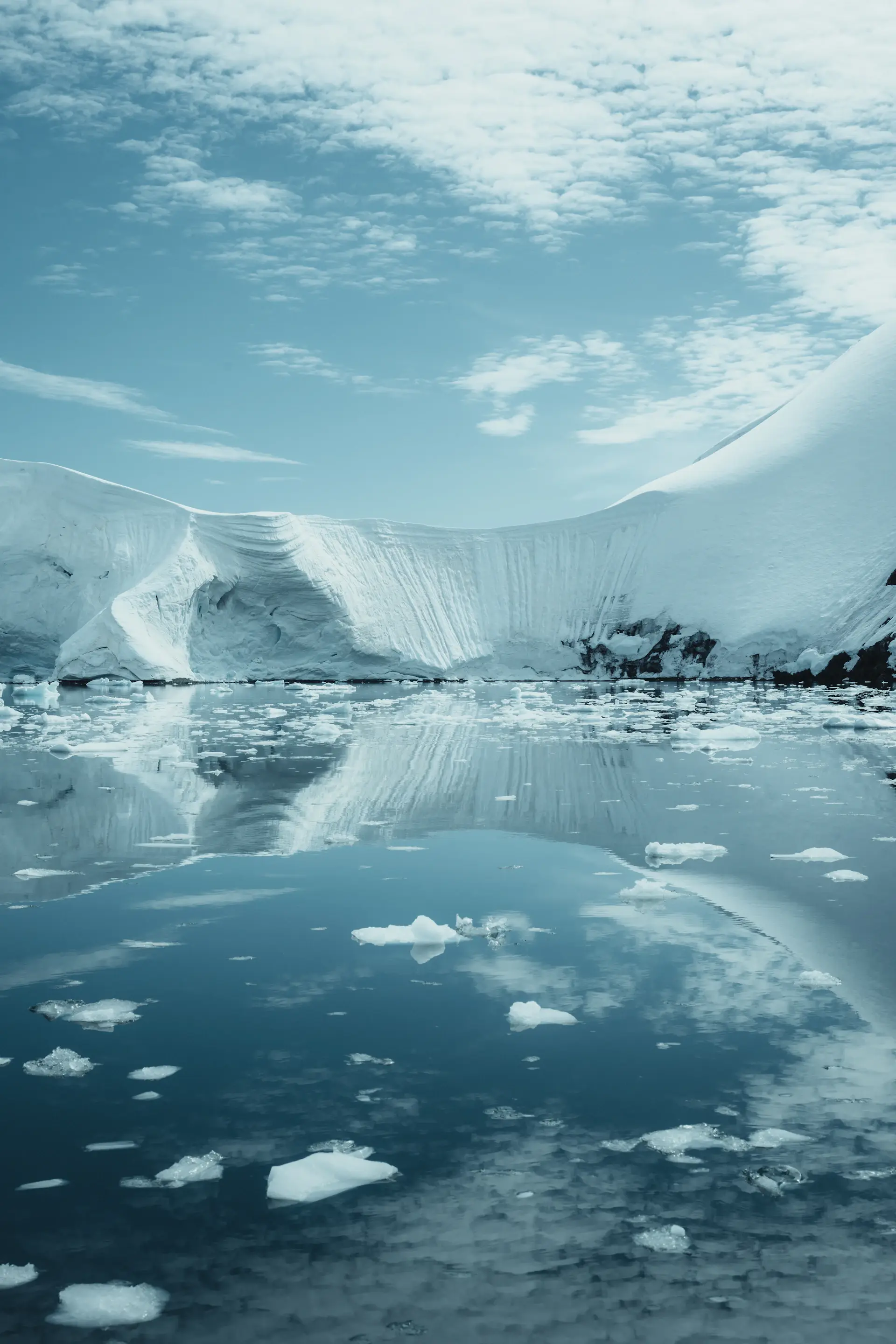 A solitary kayaker among grounded icebergs in still water