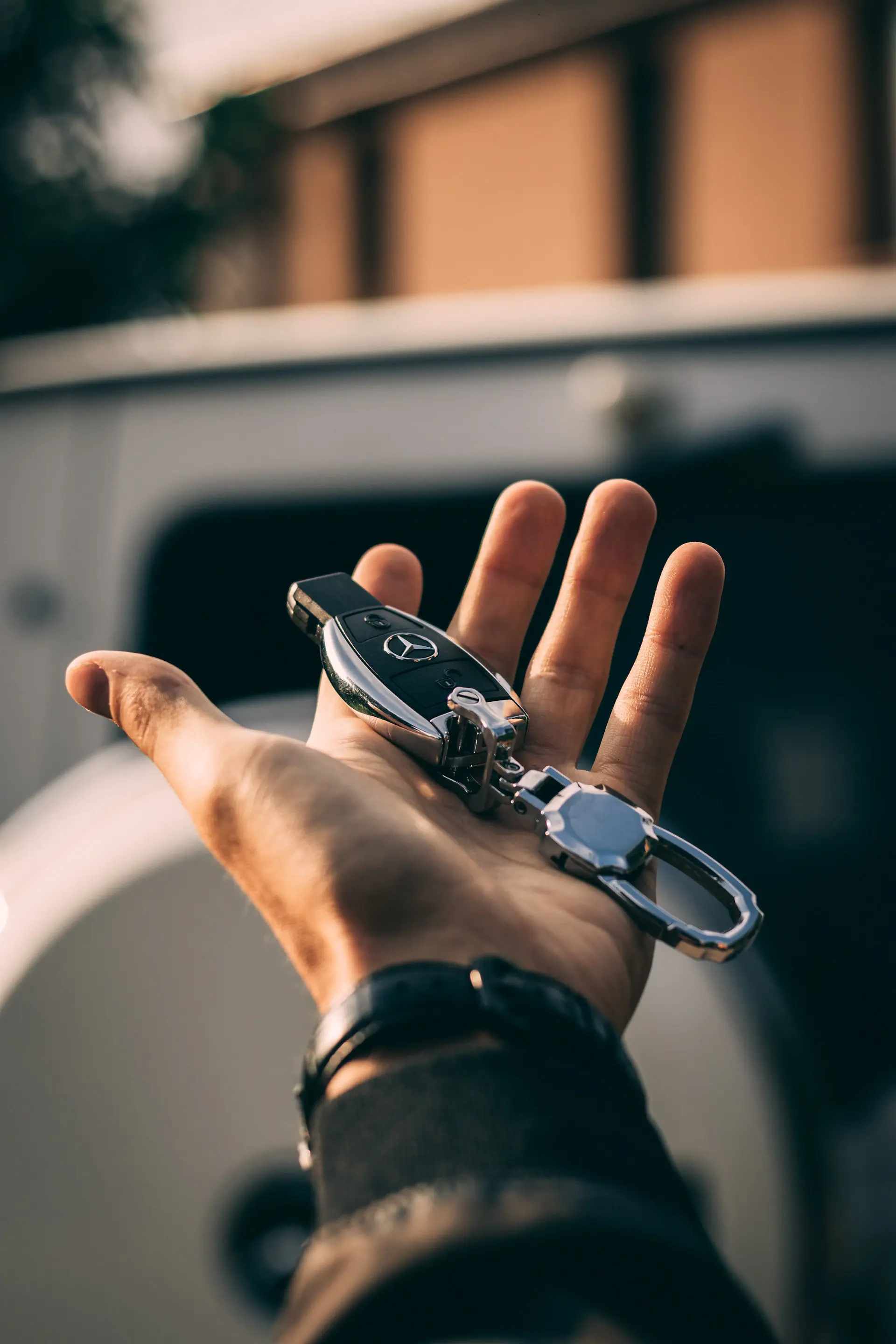 A gloved hand presenting the keys to a luxury motorcar in a private lounge
