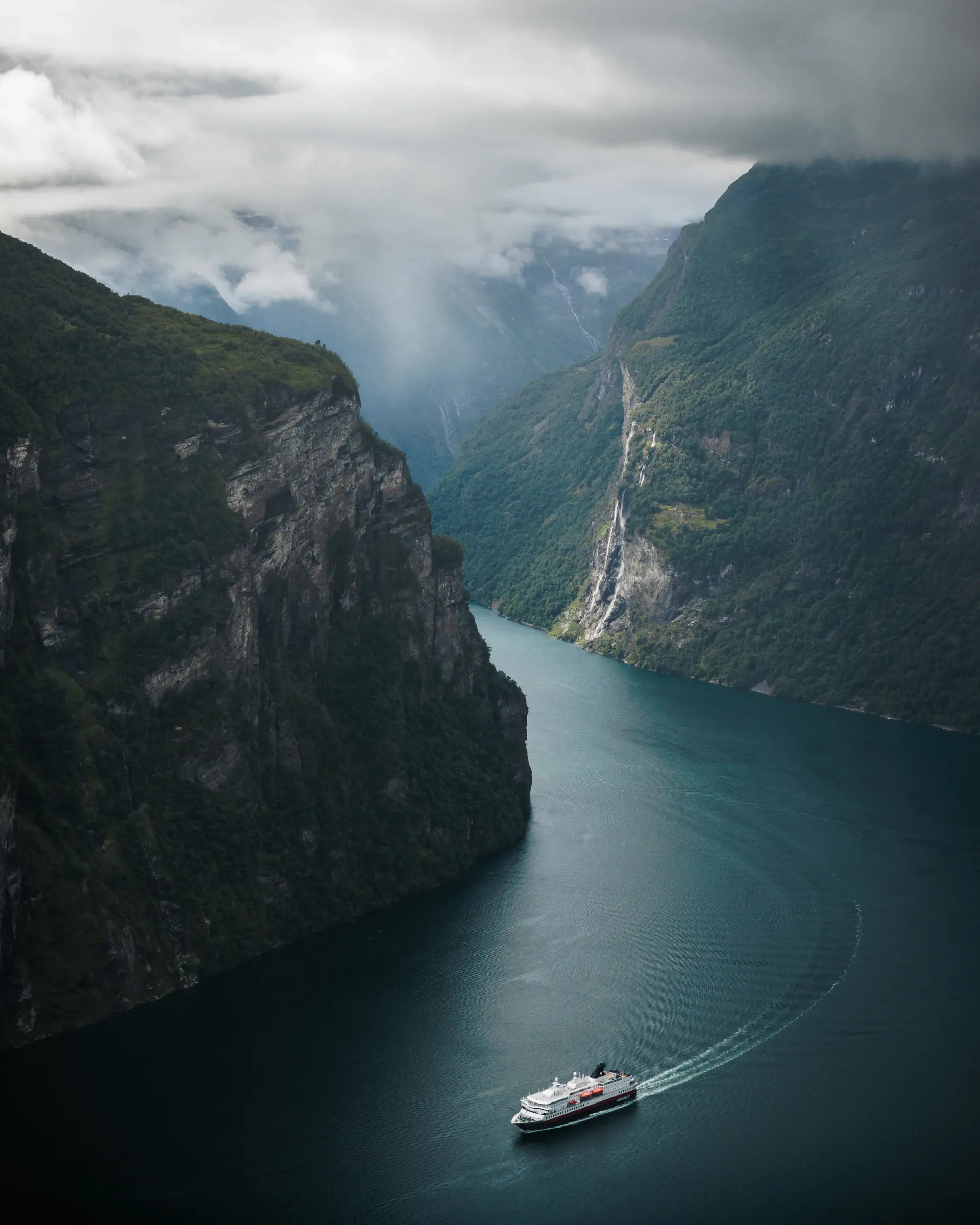 The aurora borealis over a still fjord and a lone vessel