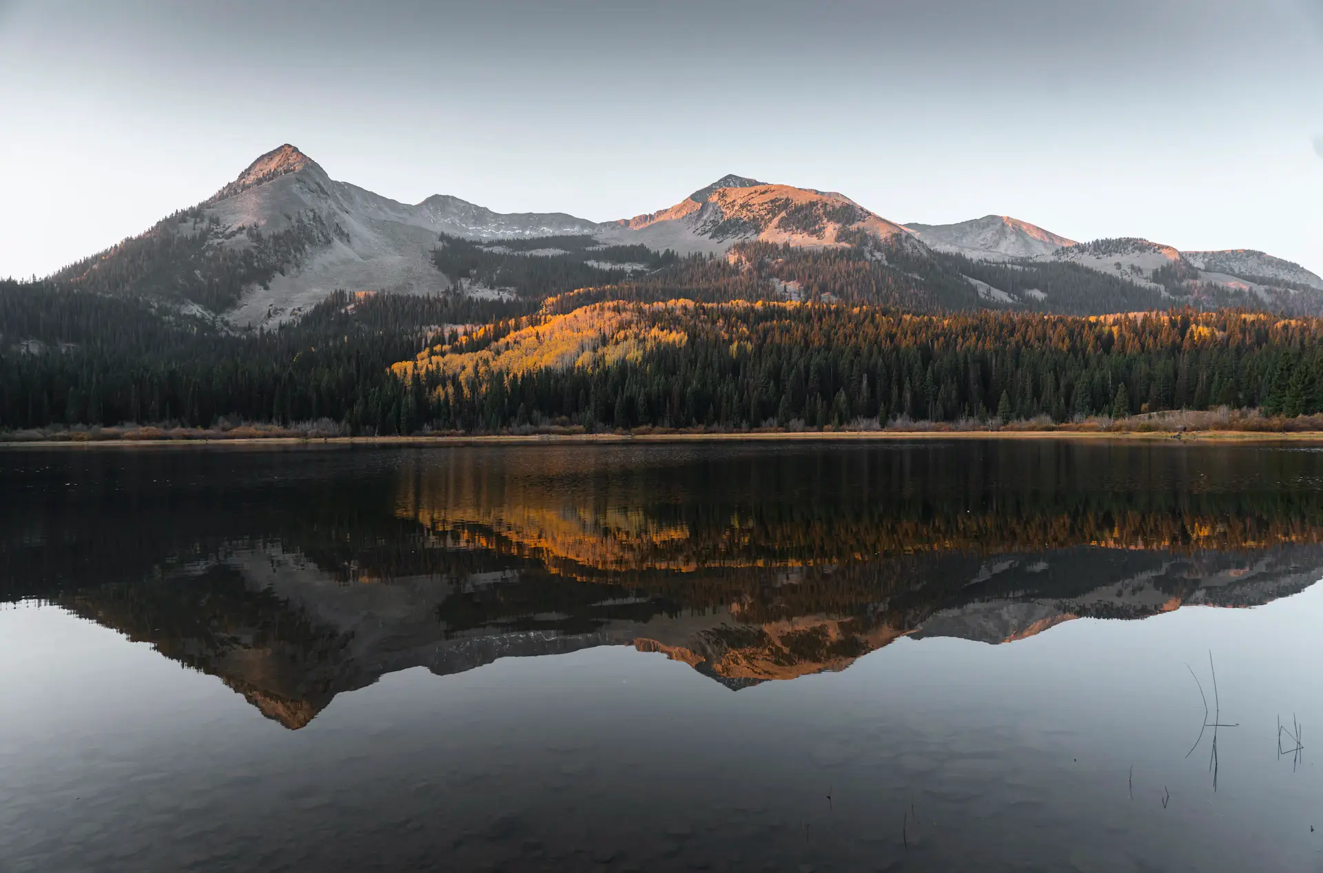 Still mountain lake mirroring the peaks at dawn