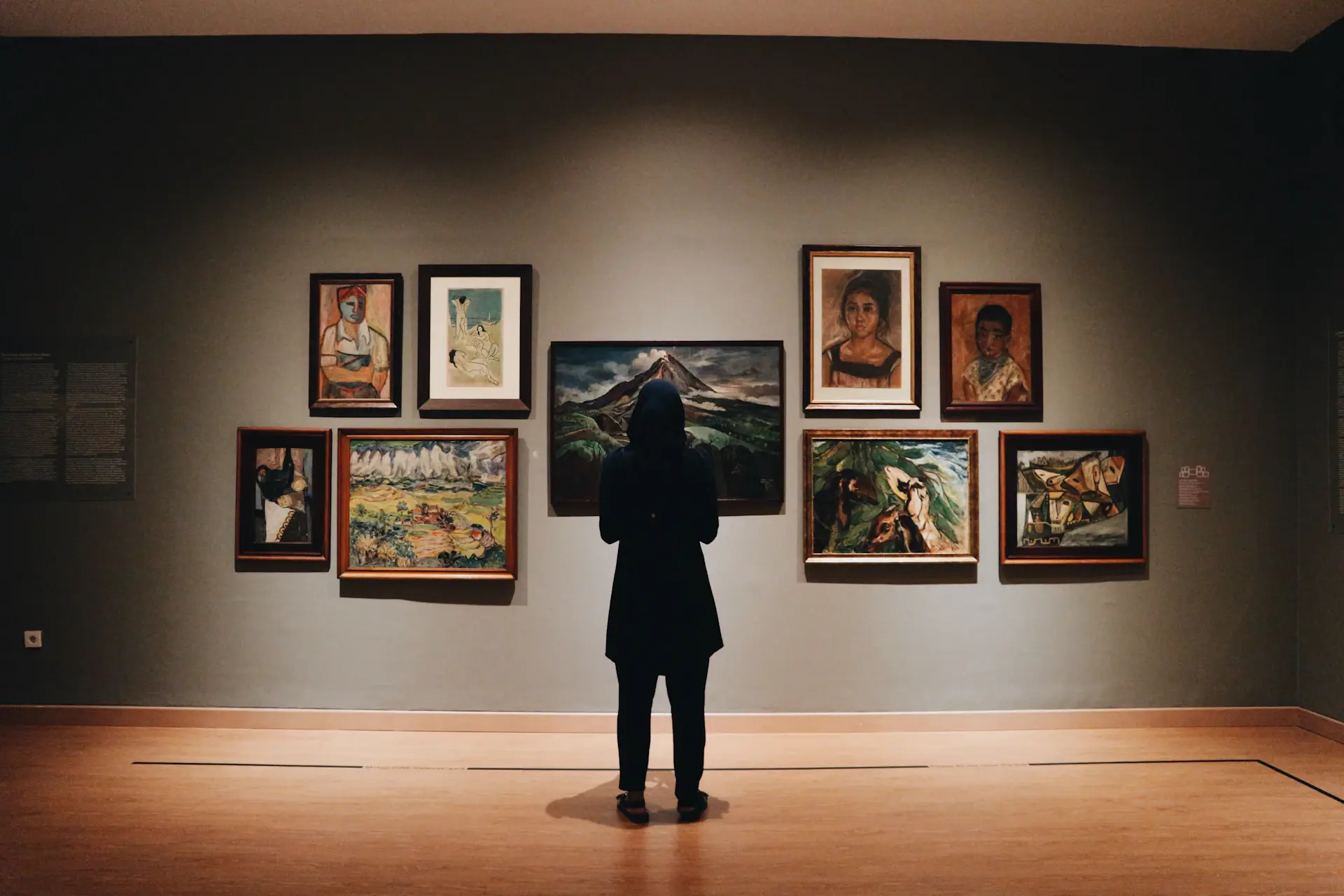 Installation view of The Weight of Light — large paintings in a dim gallery room