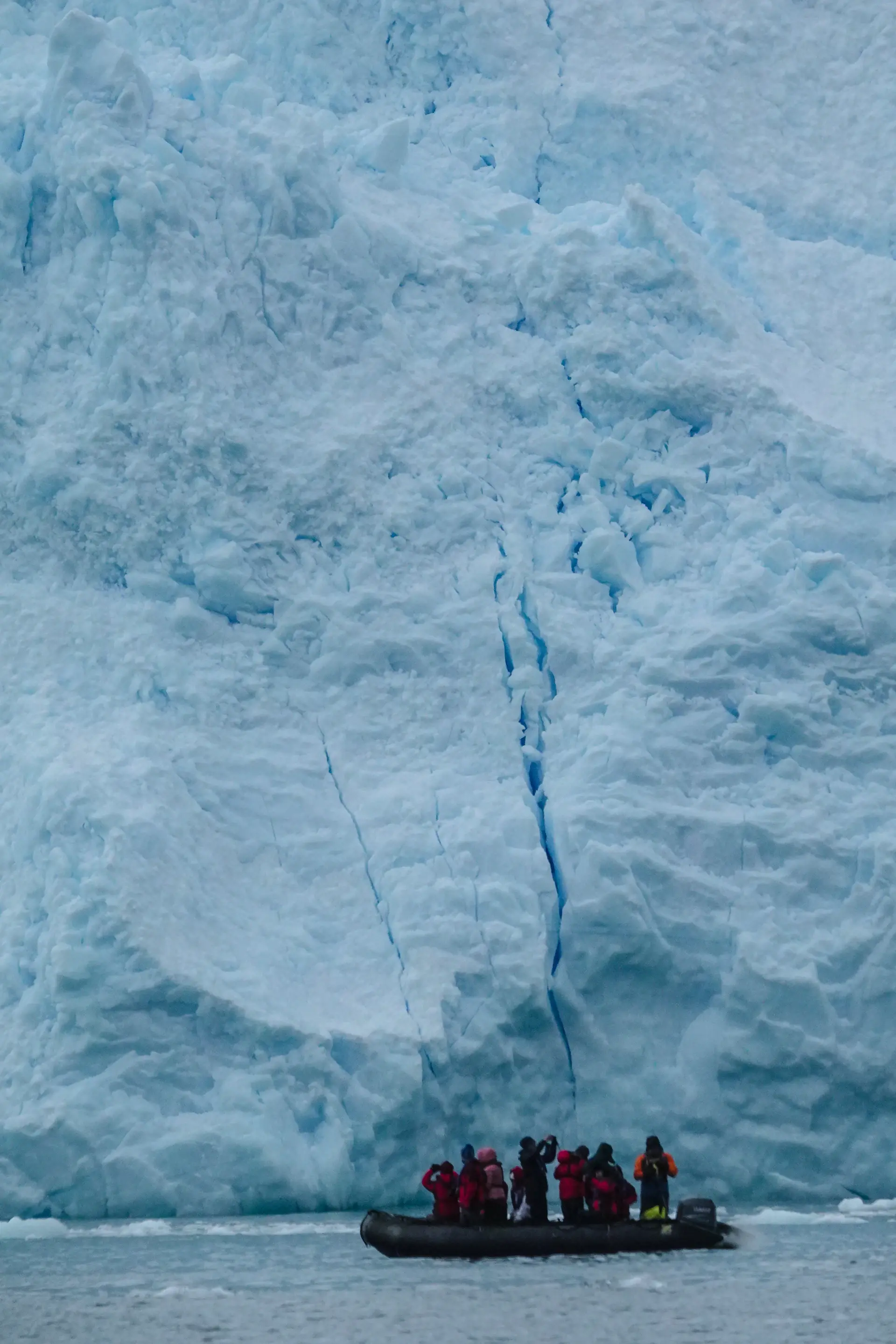 An expedition ship dwarfed by towering Antarctic ice