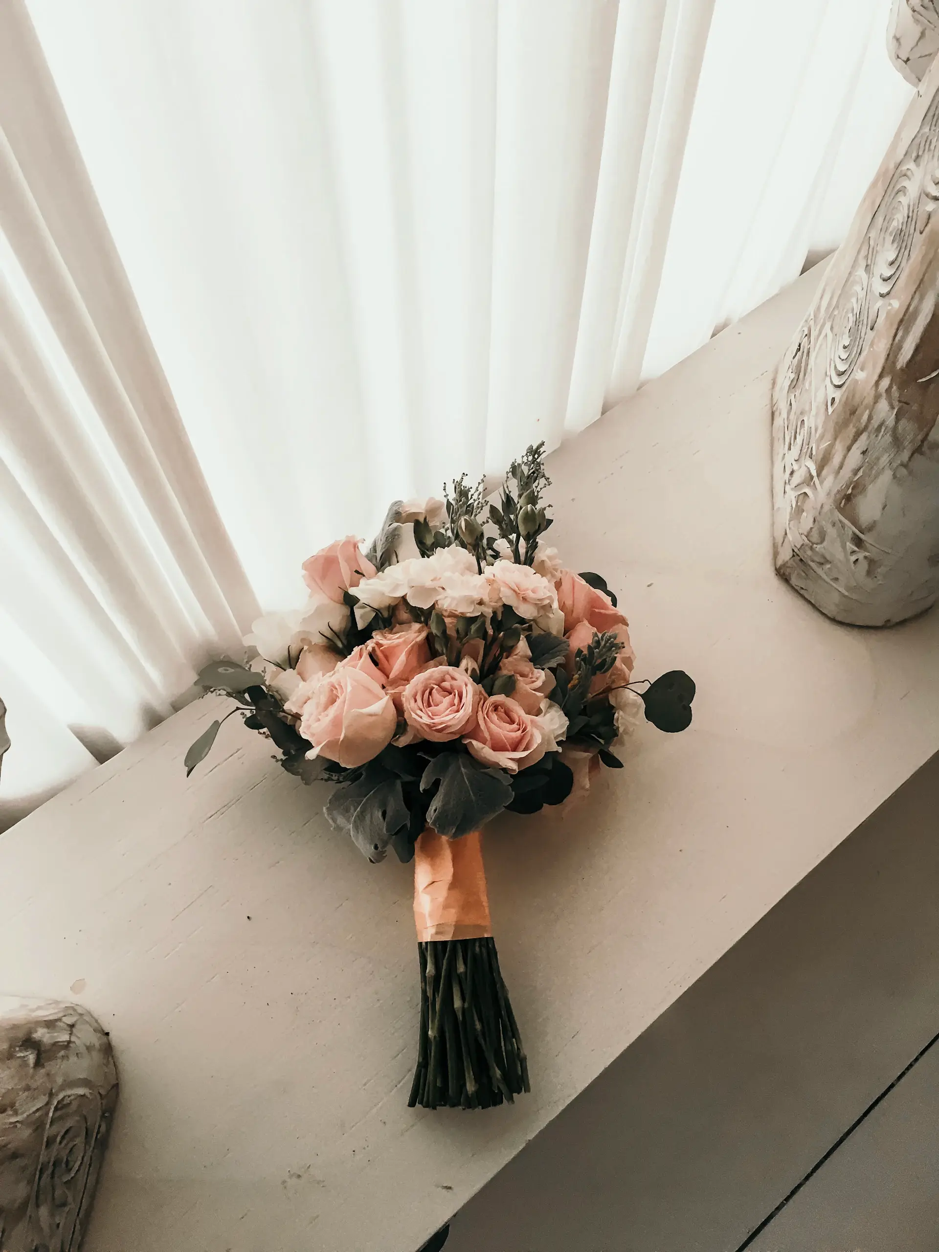 Một bó hoa hồng hoàn thiện đặt bên cửa sổ atelier