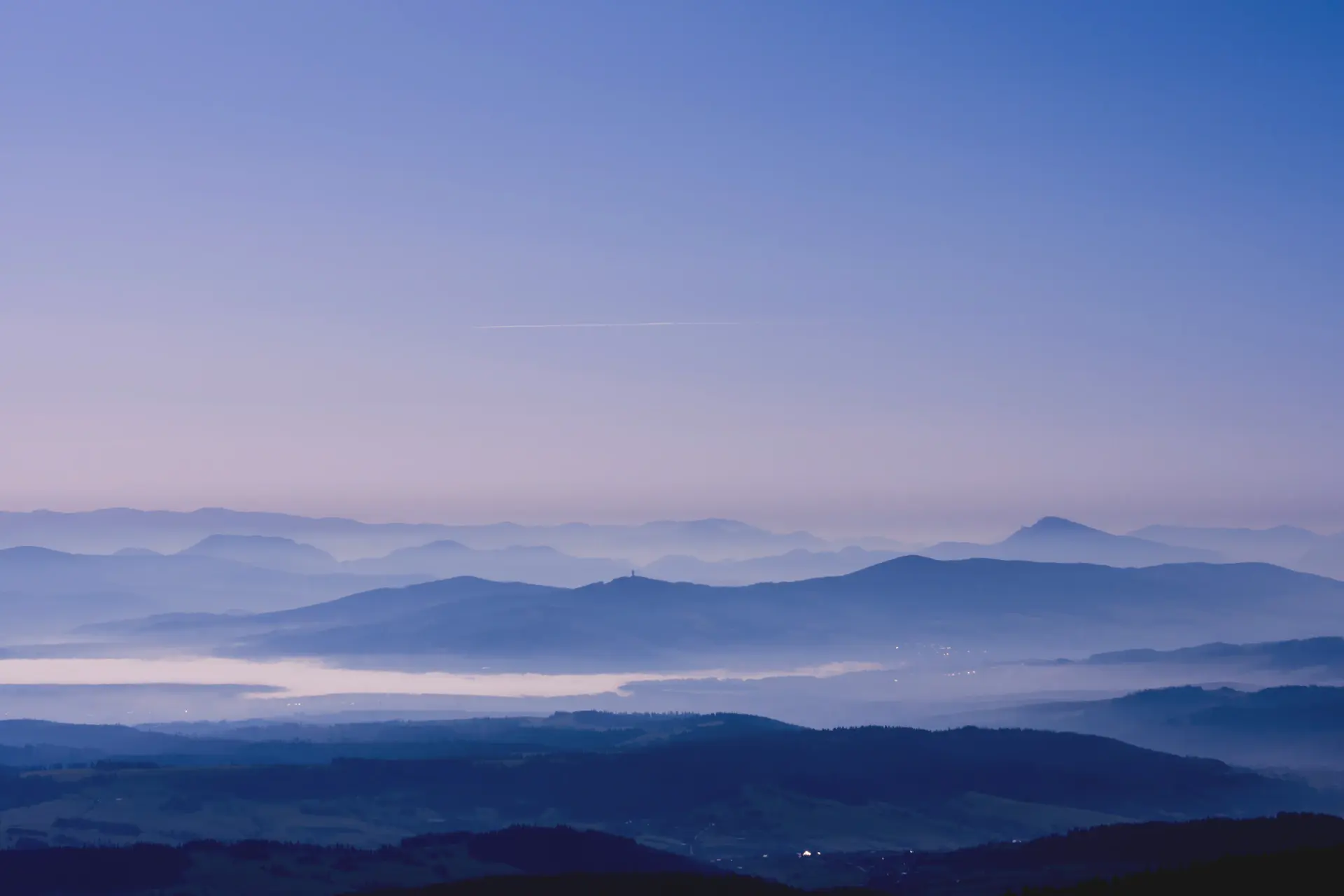 A panoramic horizon at dawn, mountains dissolving into mist