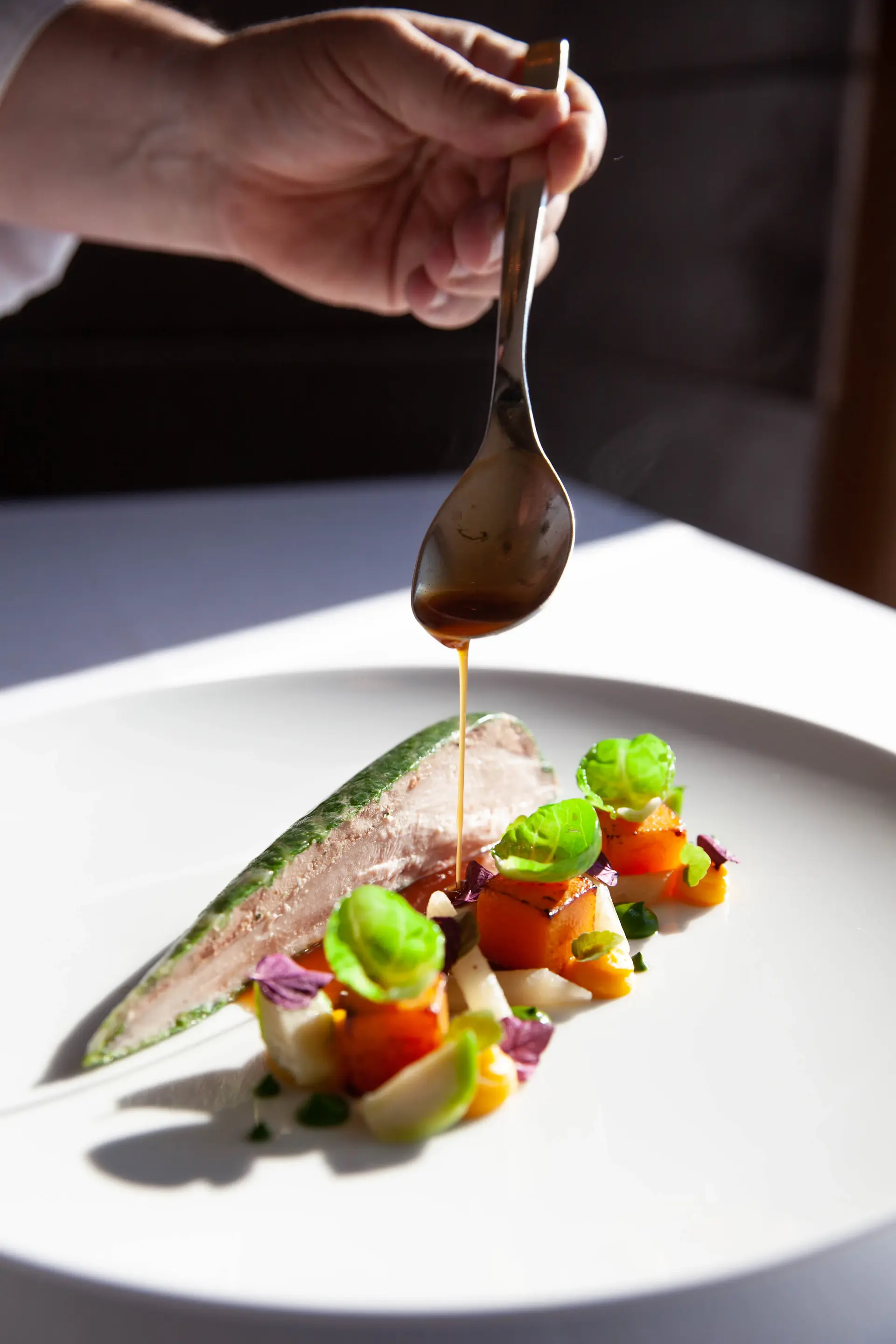 Một course của tasting menu đang được hoàn thiện bên ánh nến