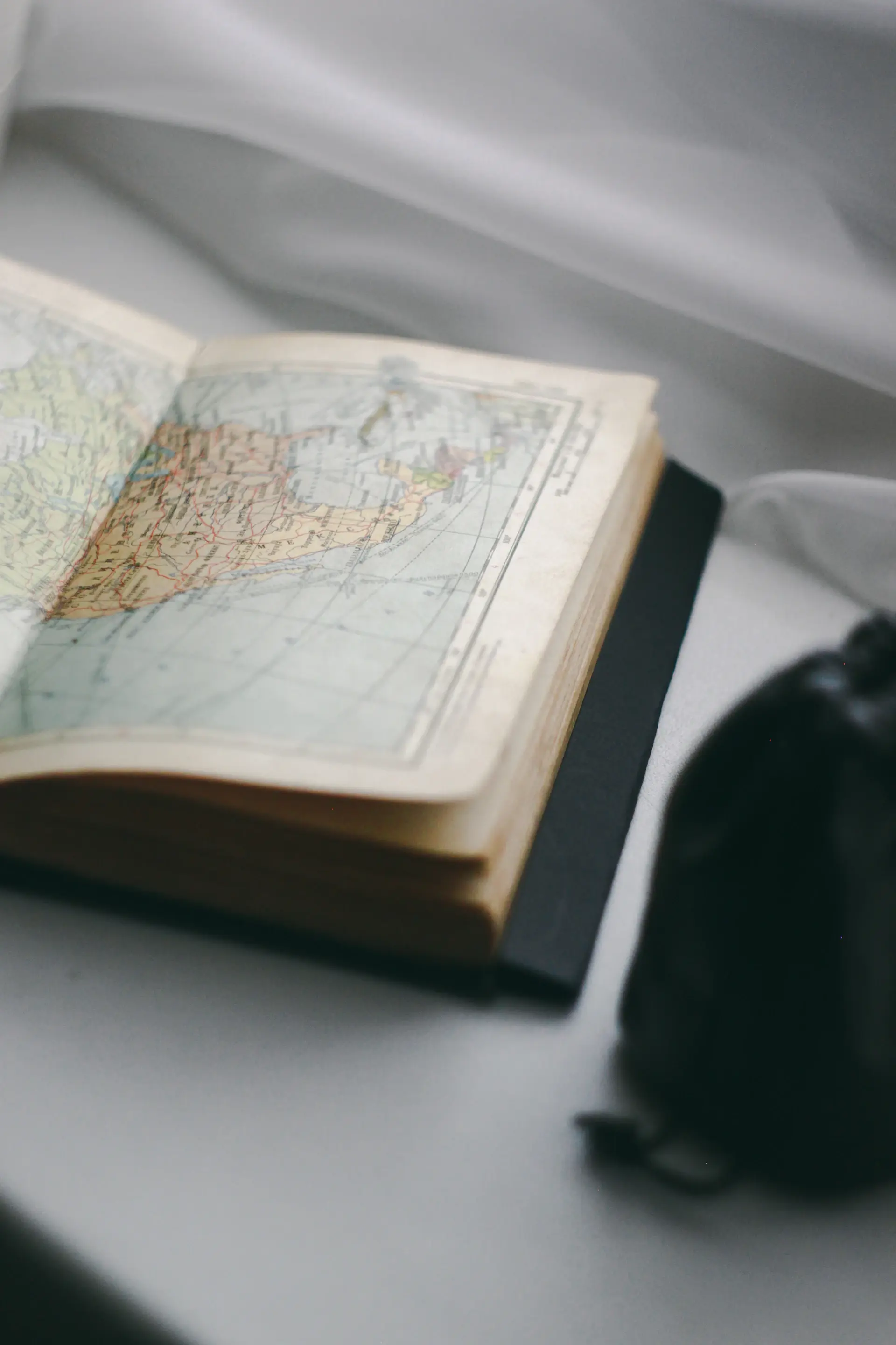 A curator's desk with maps and a single glass of champagne in soft light