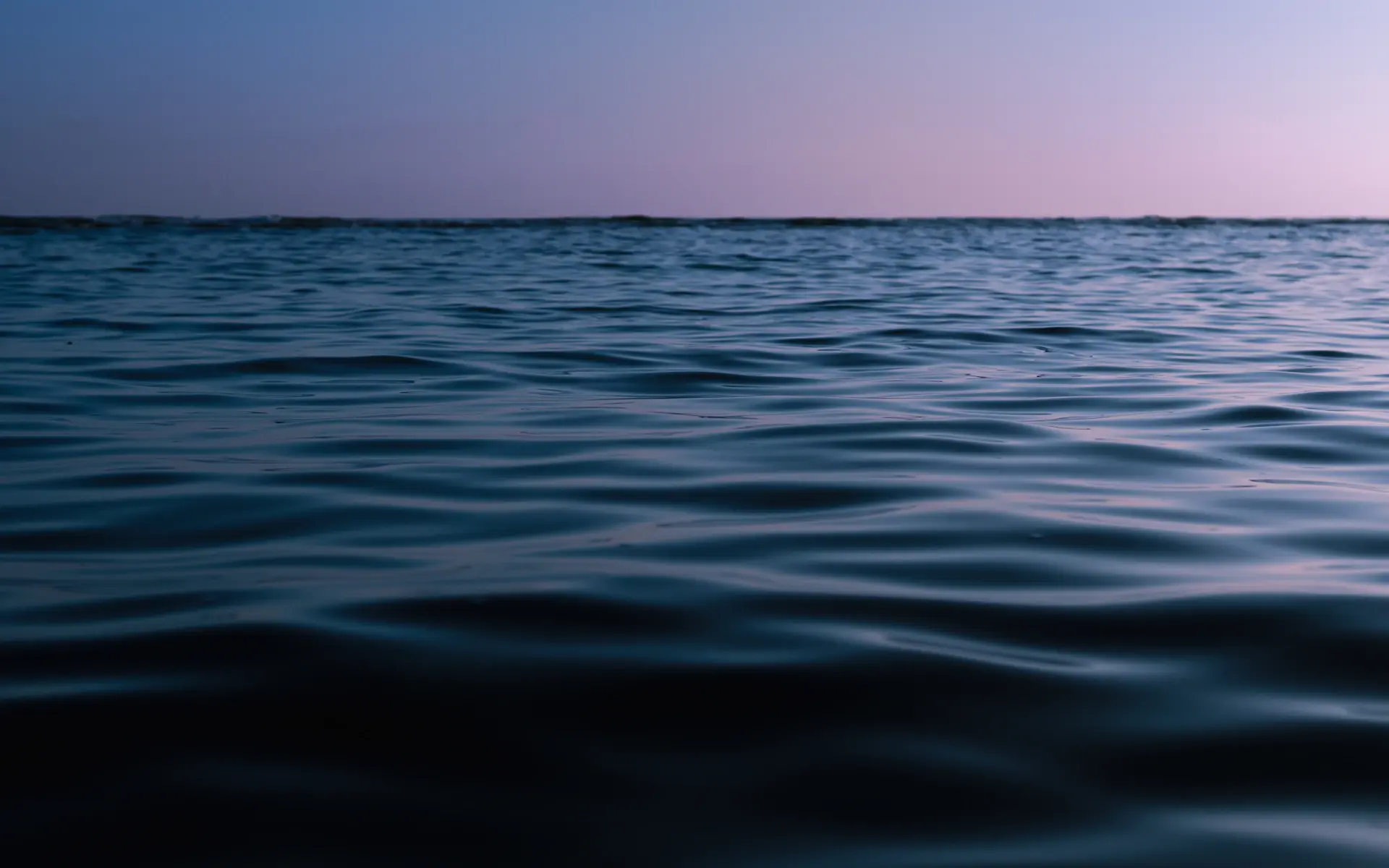 A private vessel cutting through calm polar waters at dusk