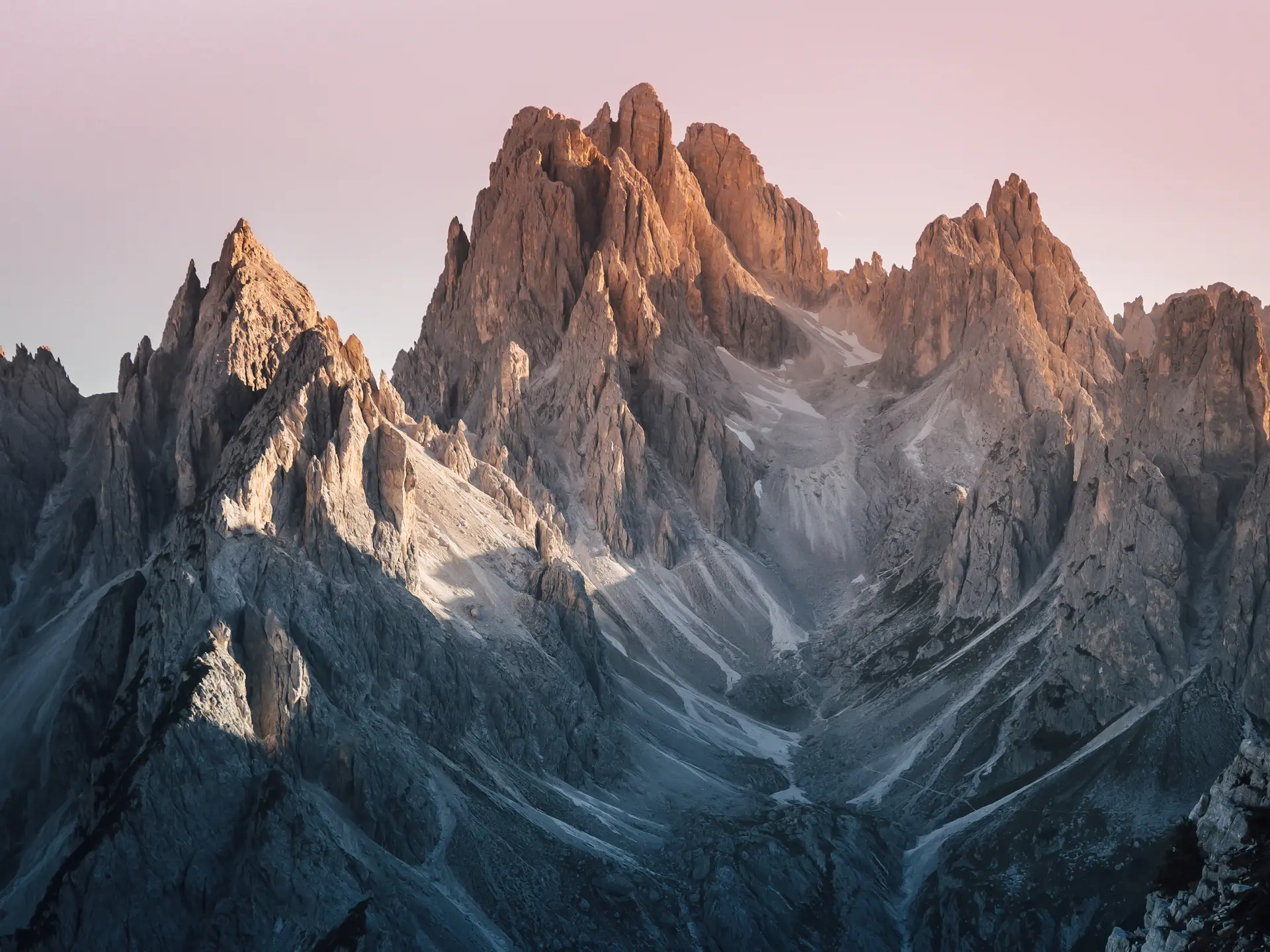 Jagged alpine peaks rising into low cloud at first light