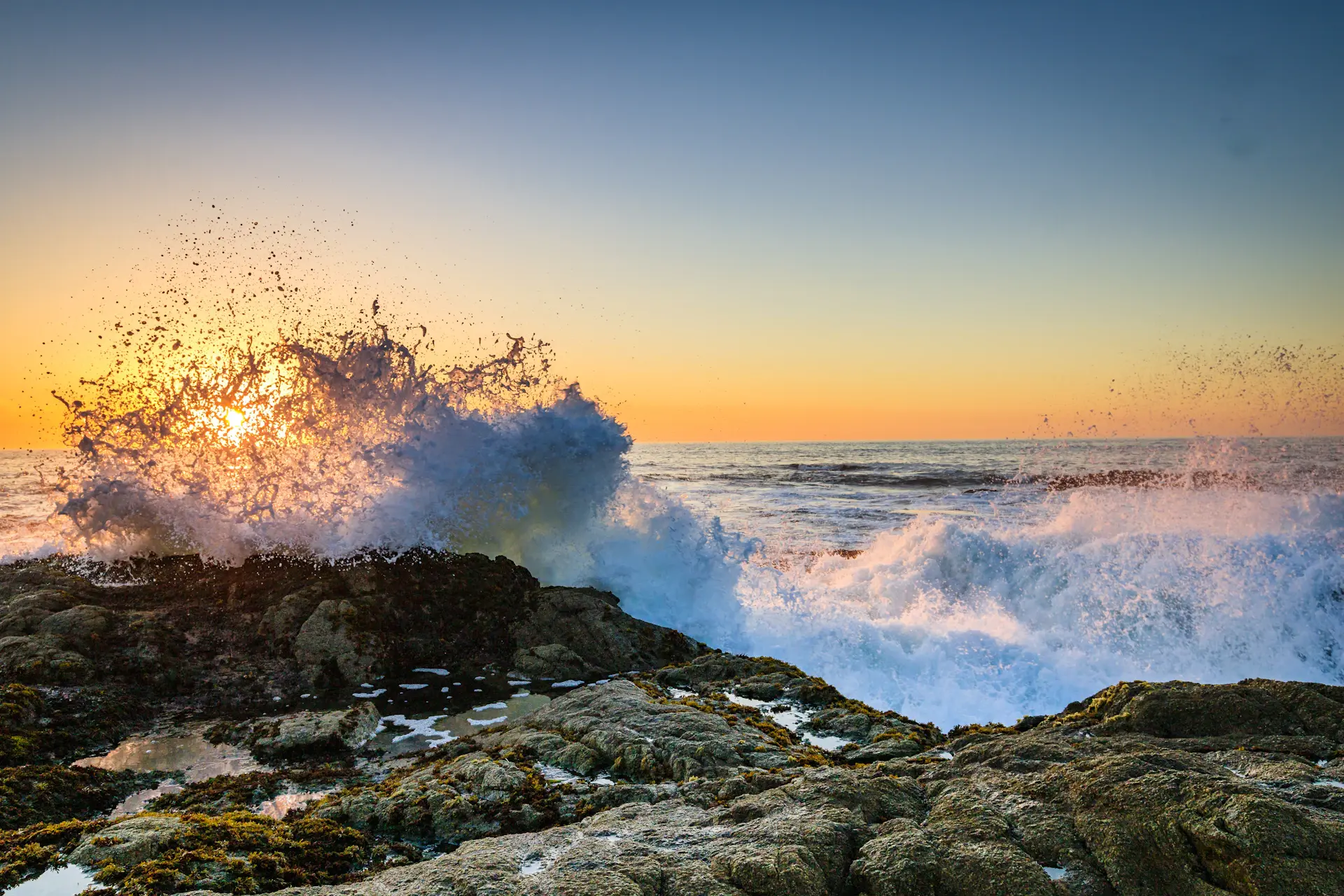 Long-exposure waves washing over dark coastal rocks at dusk