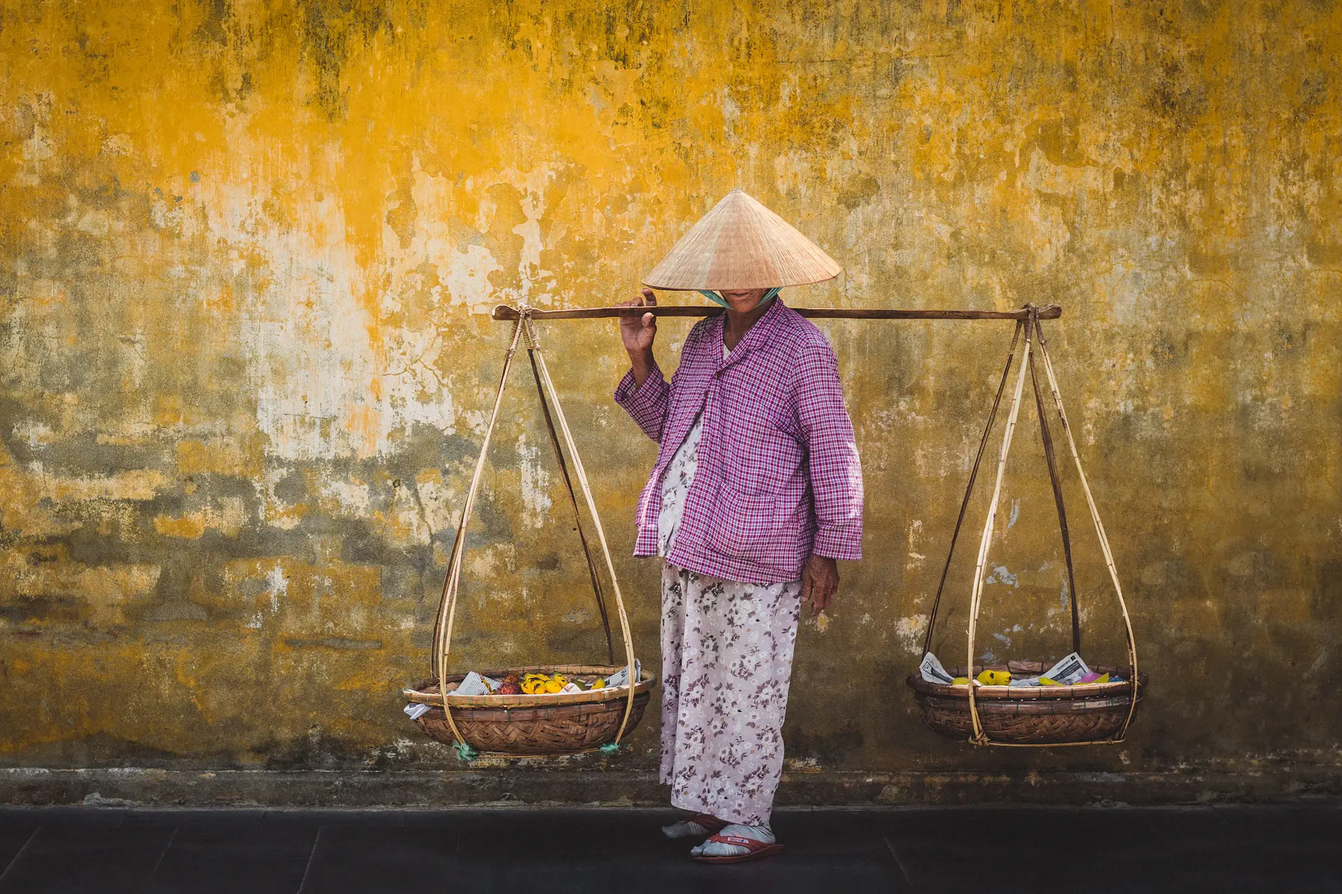 Người phụ nữ đứng bán rau tại sạp hàng nhỏ trong chợ truyền thống