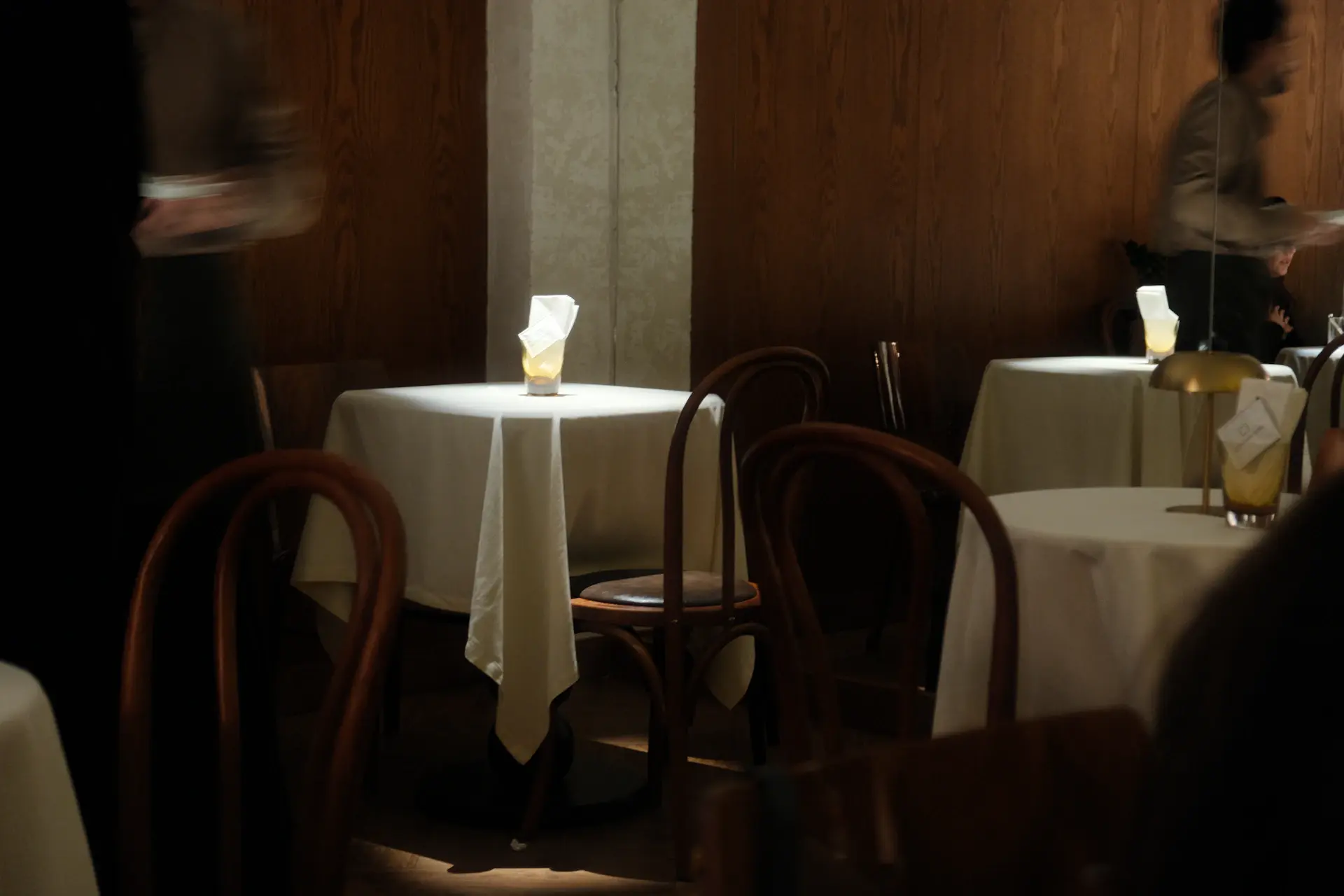 Empty cafe table set up at golden hour with candles and porcelain