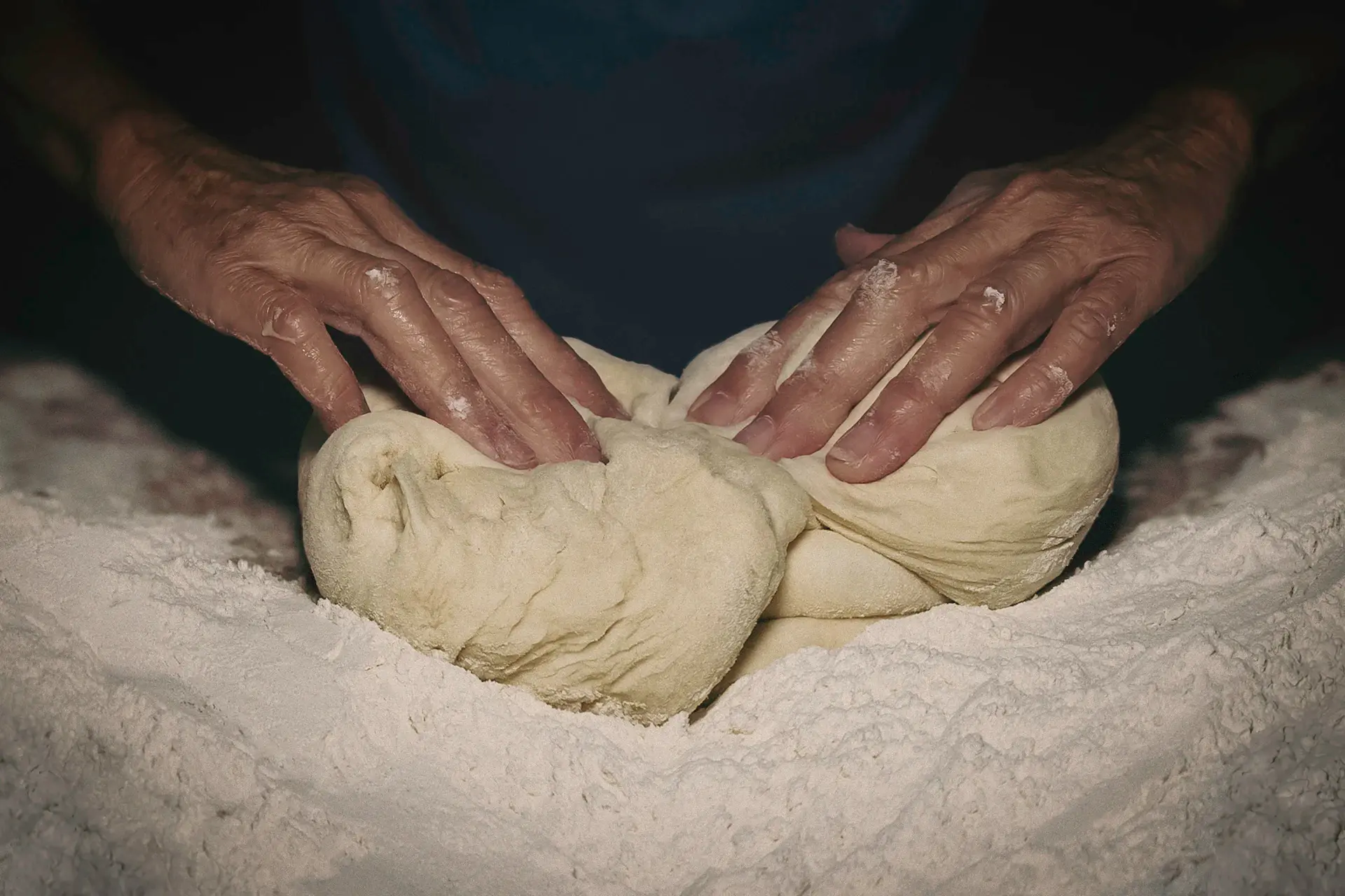 Hands shaping dough on a floured countertop