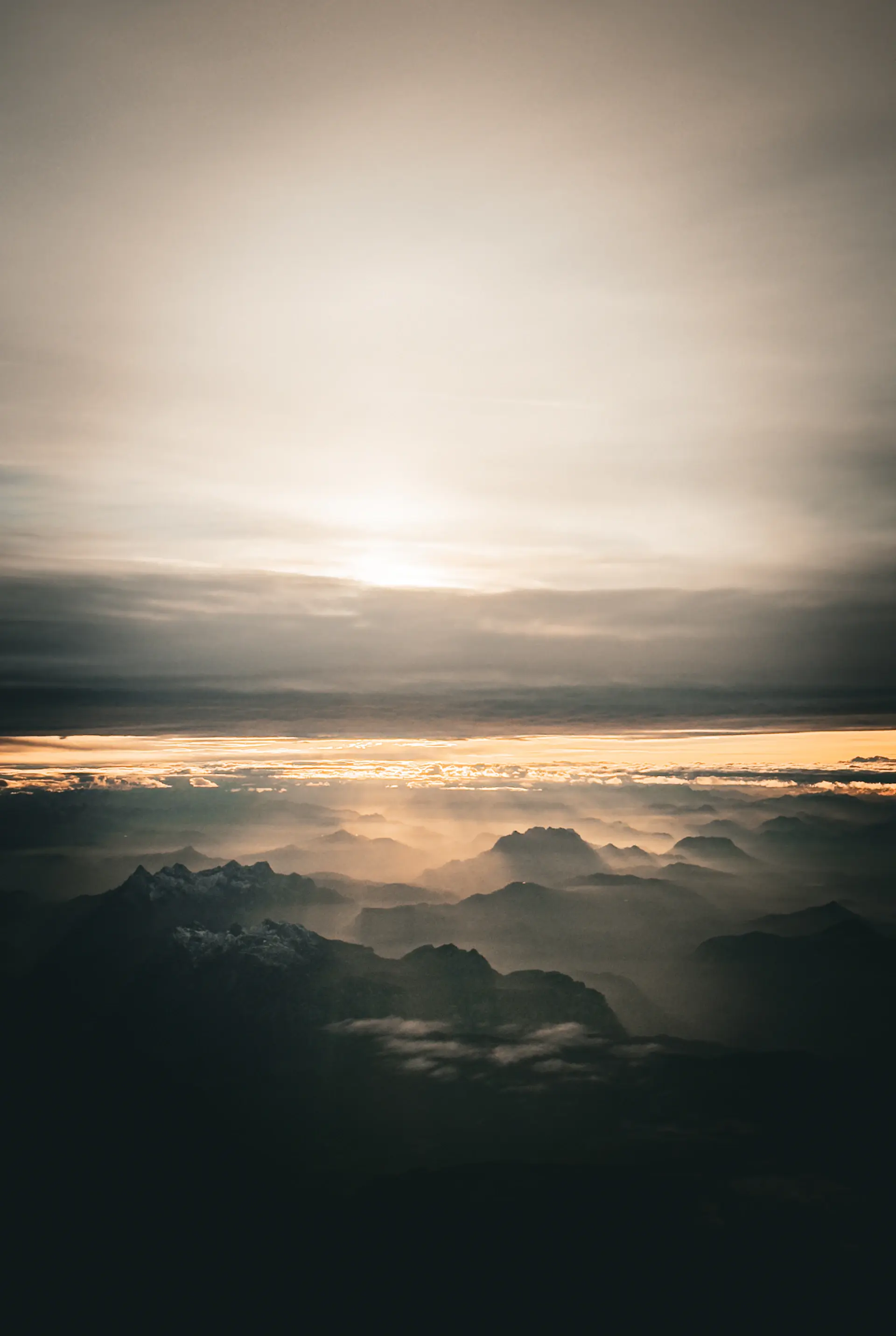 Alpine peaks glowing at sunrise above a cloud inversion