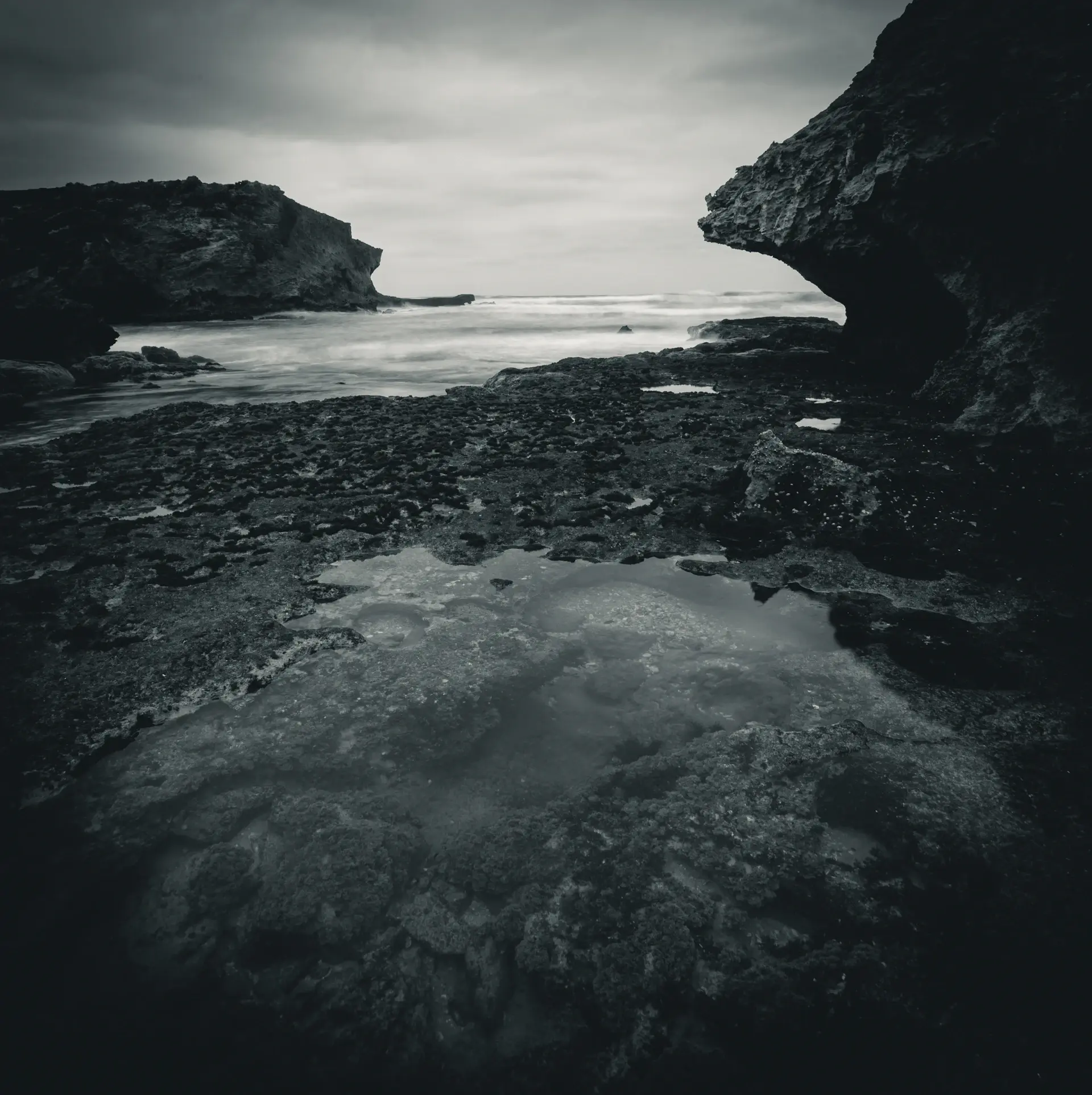 Rock tide pools reflecting an overcast sky