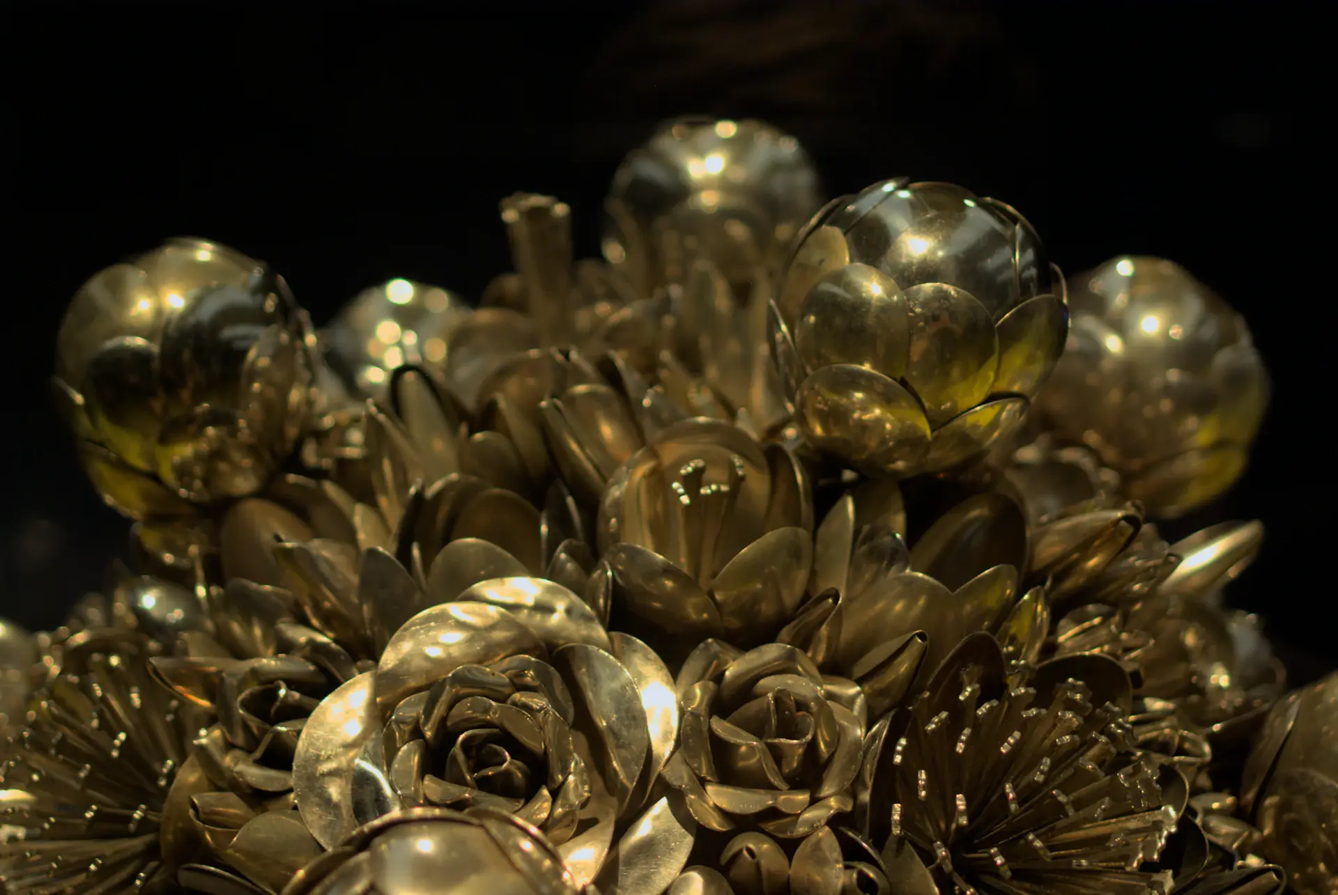 Detail of a gilded table setting with candlelight and roses