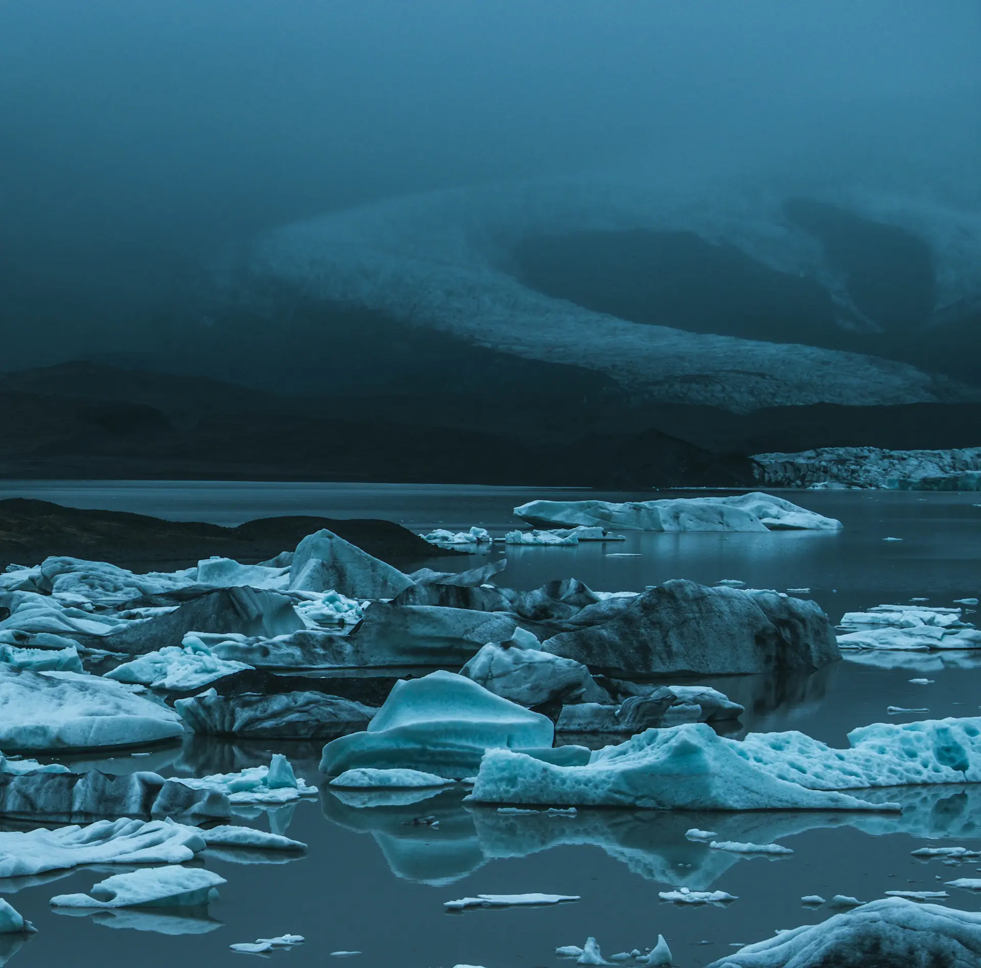Sculpted blue iceberg reflected in still water