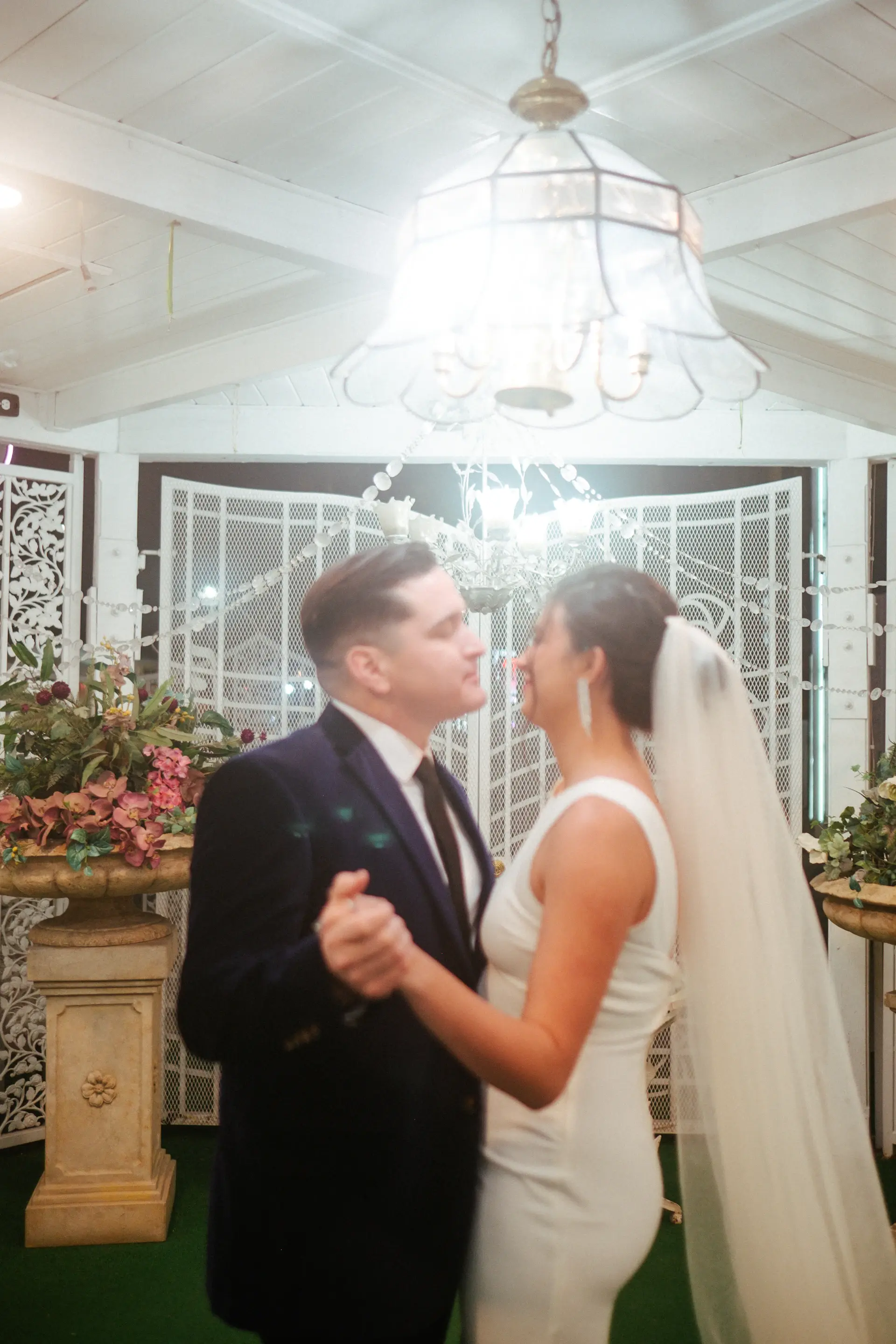 Couple sharing a first dance beneath crystal chandeliers