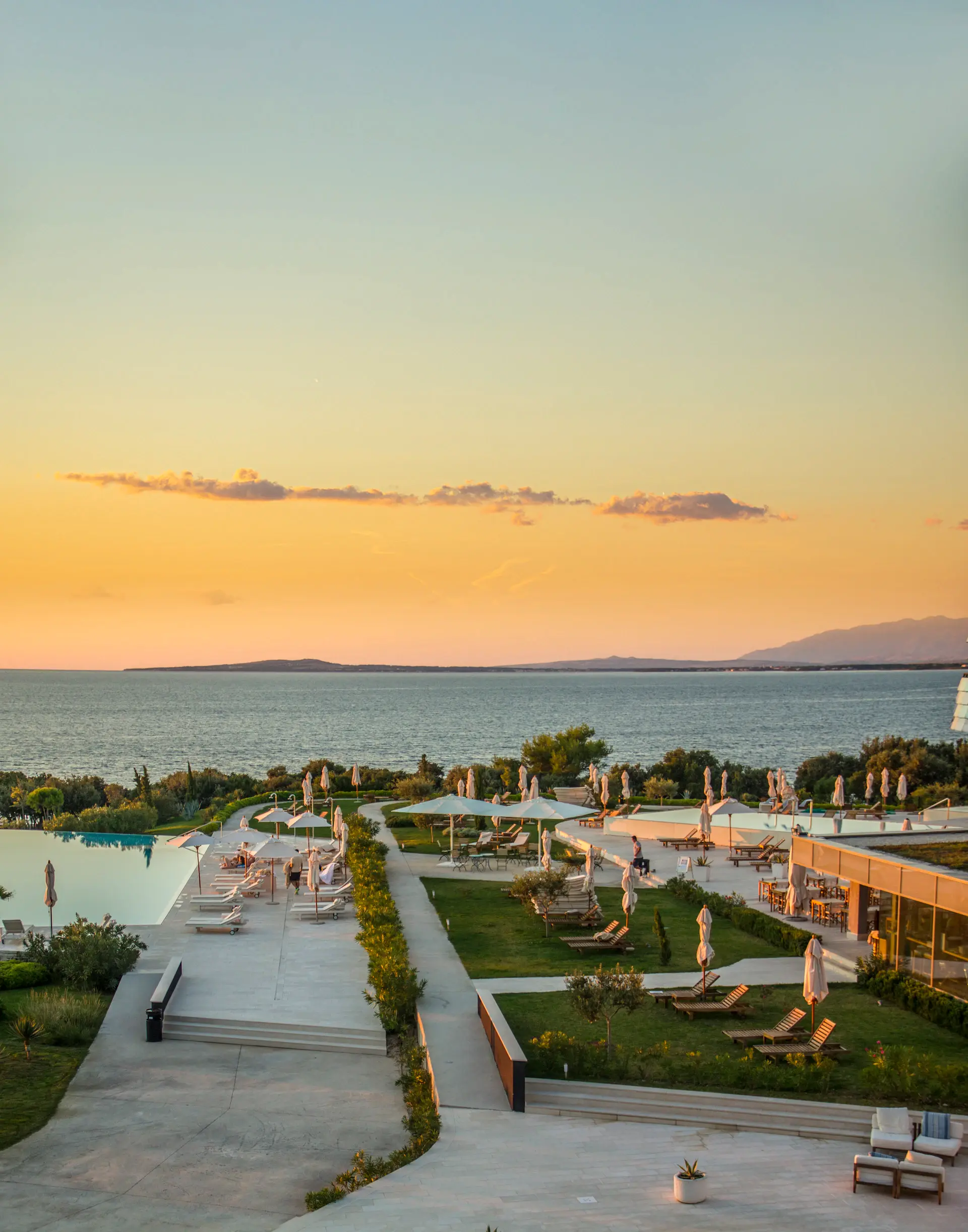A calm, sunlit terrace overlooking a remote coastline at golden hour