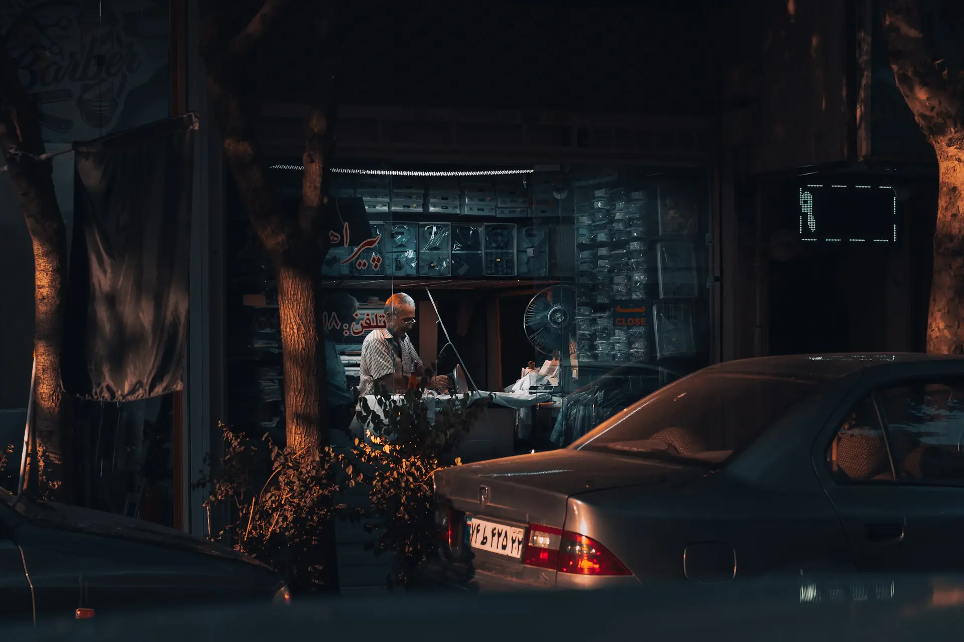 An artisan working alone in a softly lit luxury car atelier at night