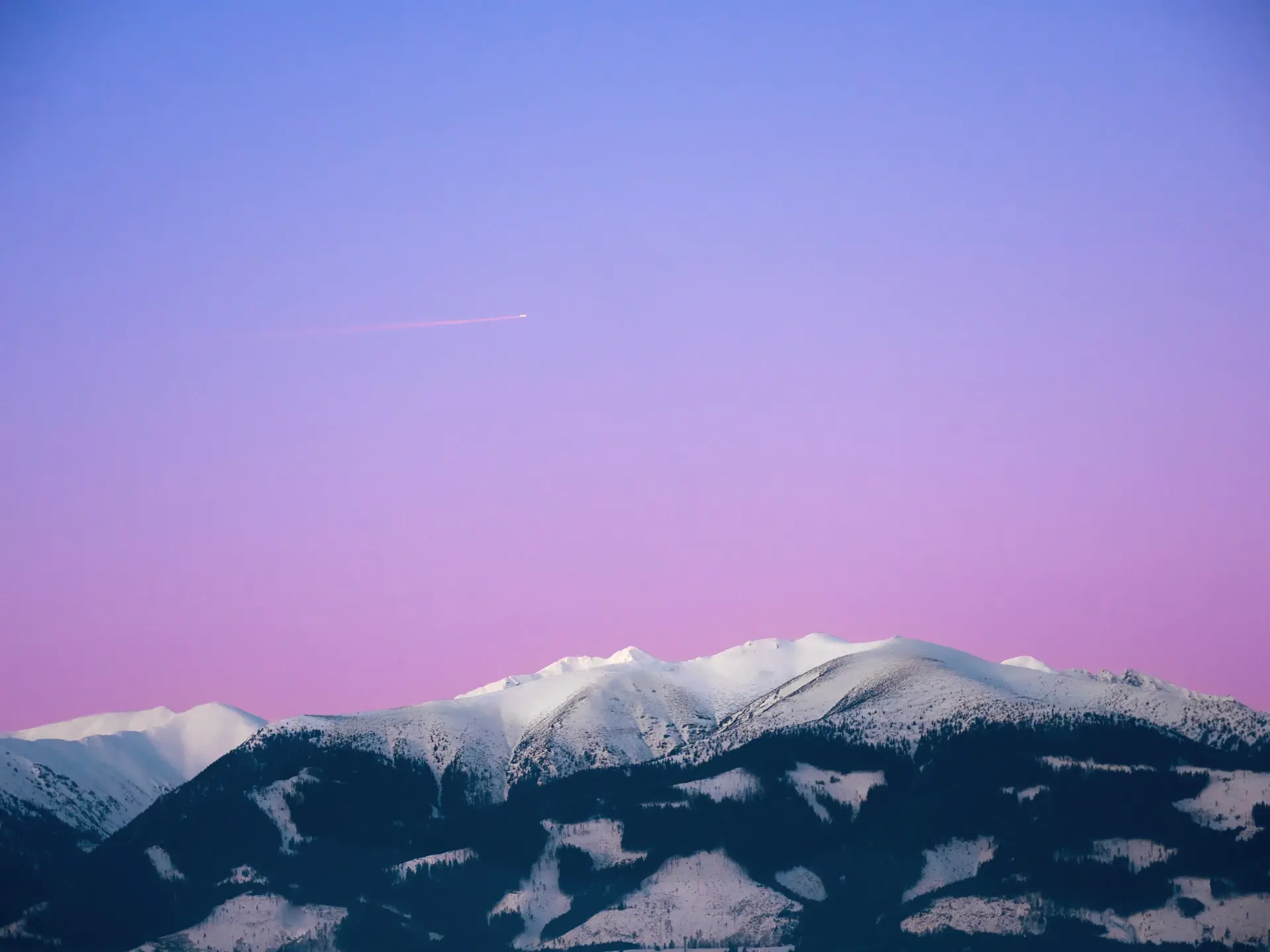 Fading pink alpenglow on distant snow peaks