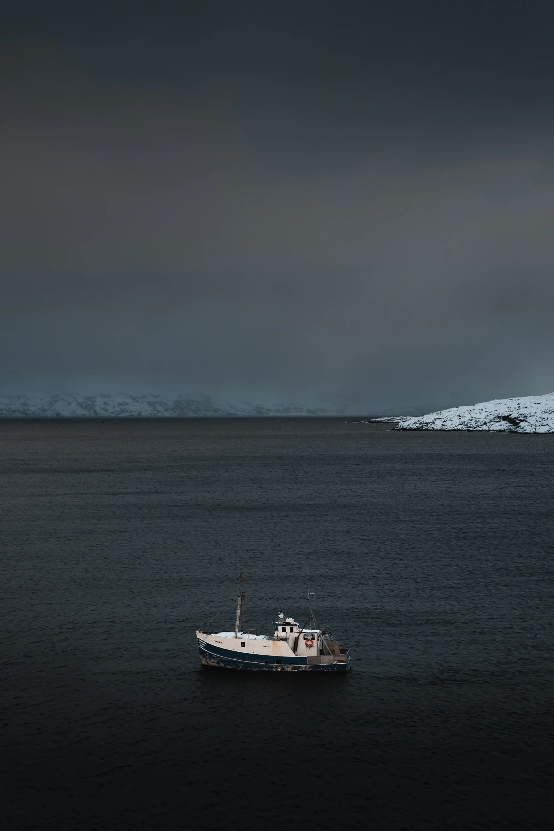 A lone expedition vessel drifting through still polar waters at first light