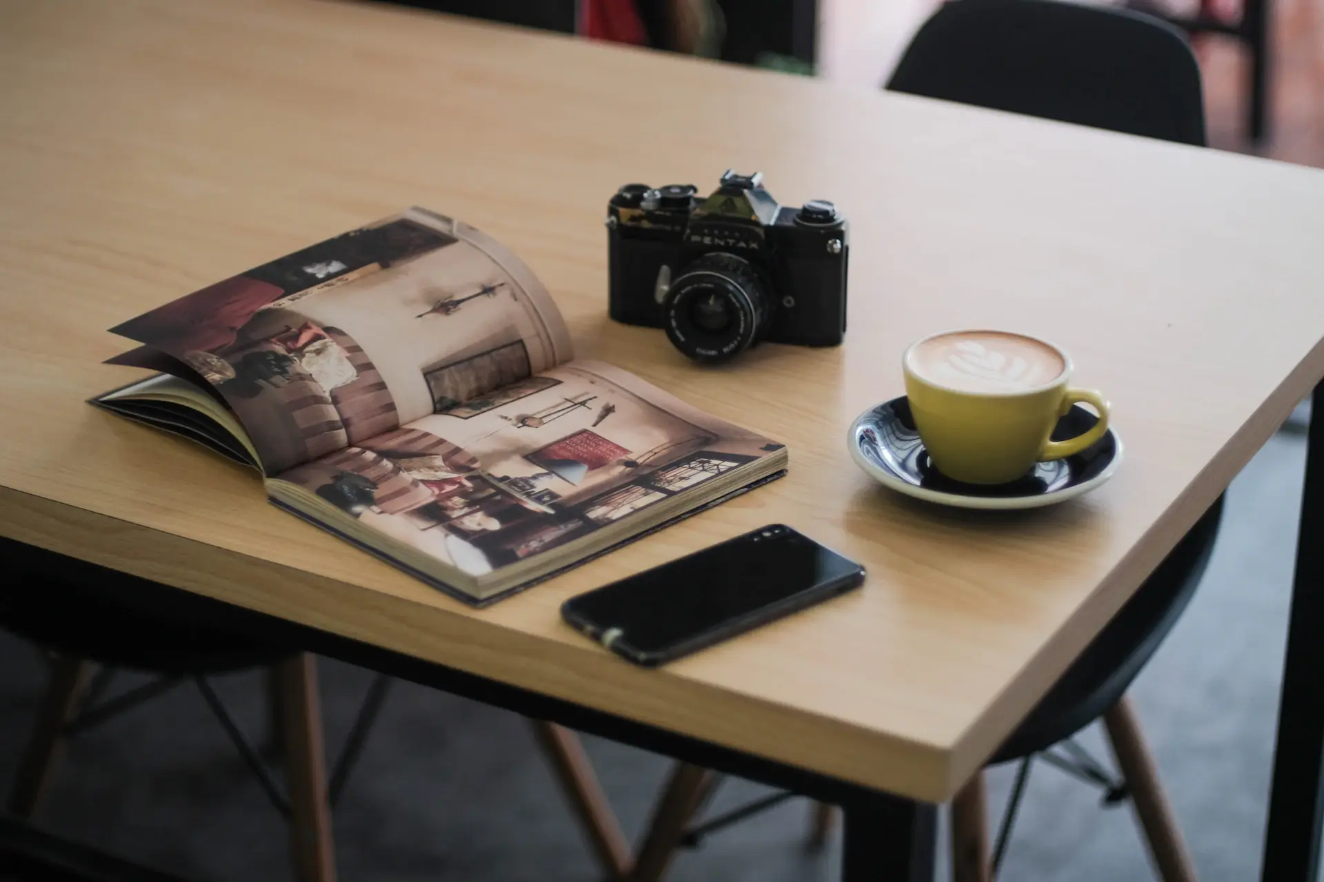 Open book on a cafe table beside a half-finished latte
