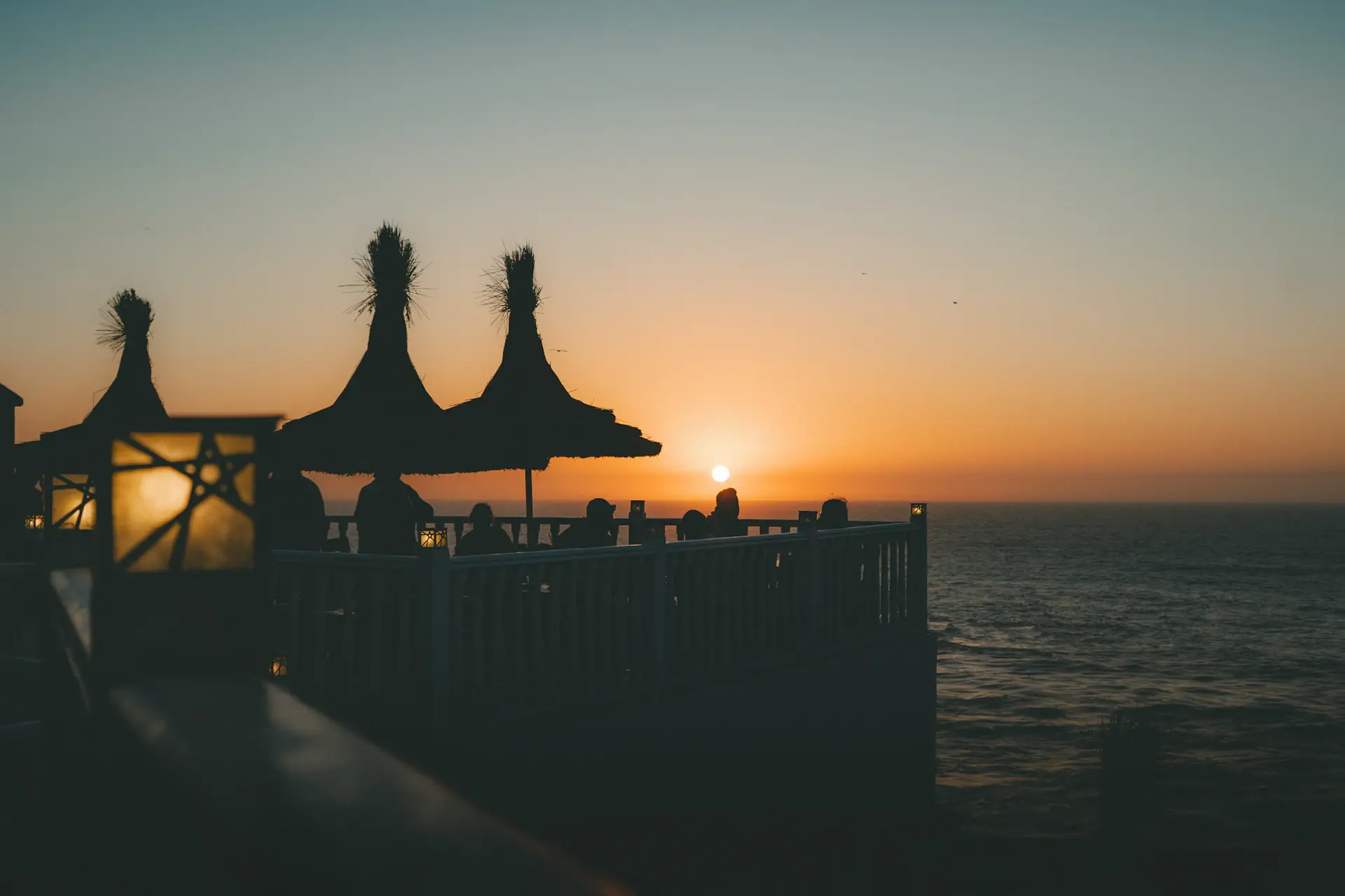Candlelit dinner table set on a seaside terrace at dusk