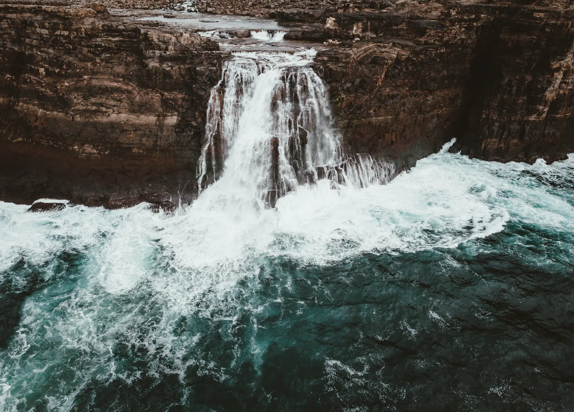 A wide curtain of water falling along a sheer cliff