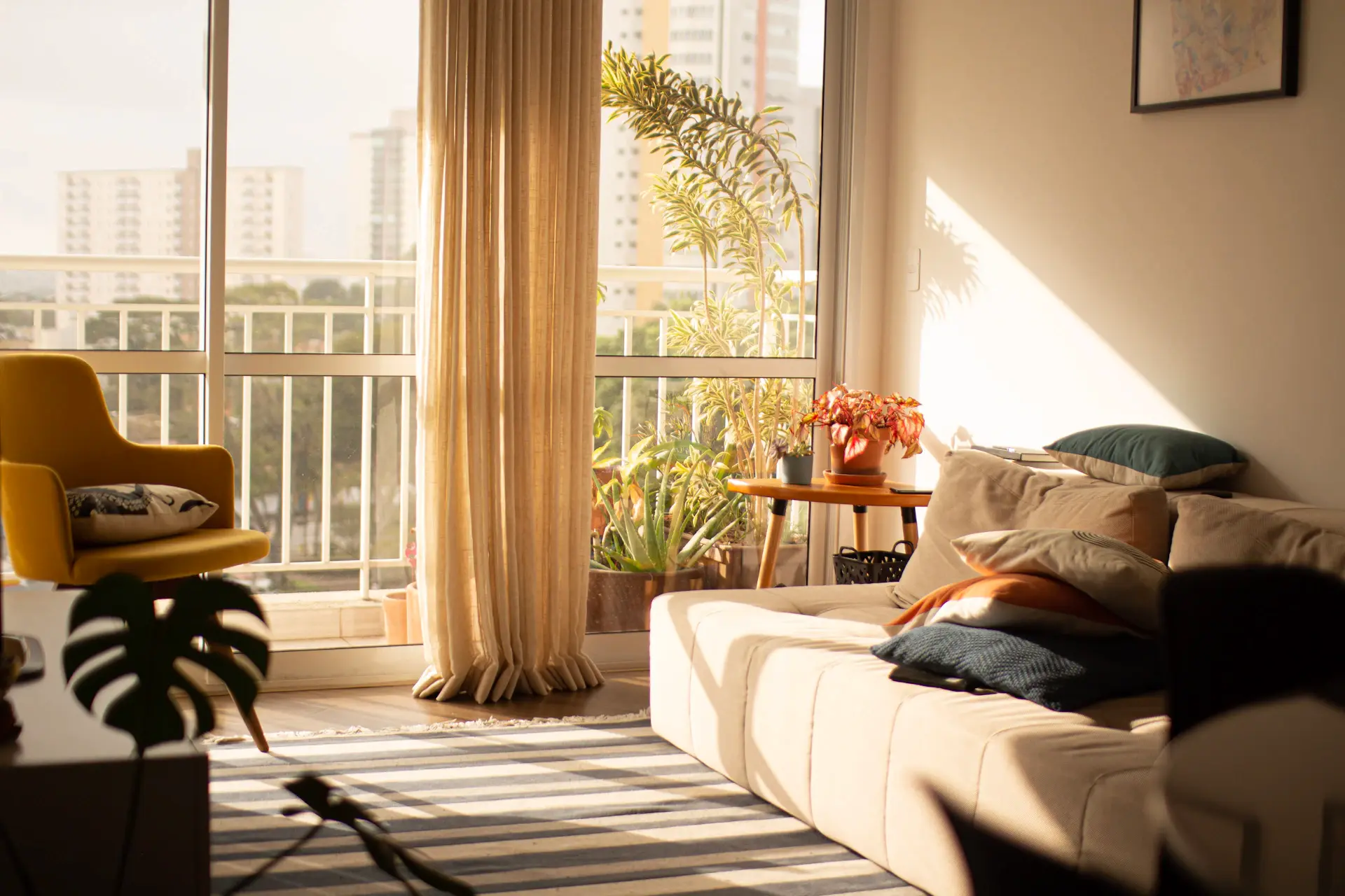 Phòng khách warm minimalism với cửa sổ lớn, ánh nắng chiều rọi qua rèm linen