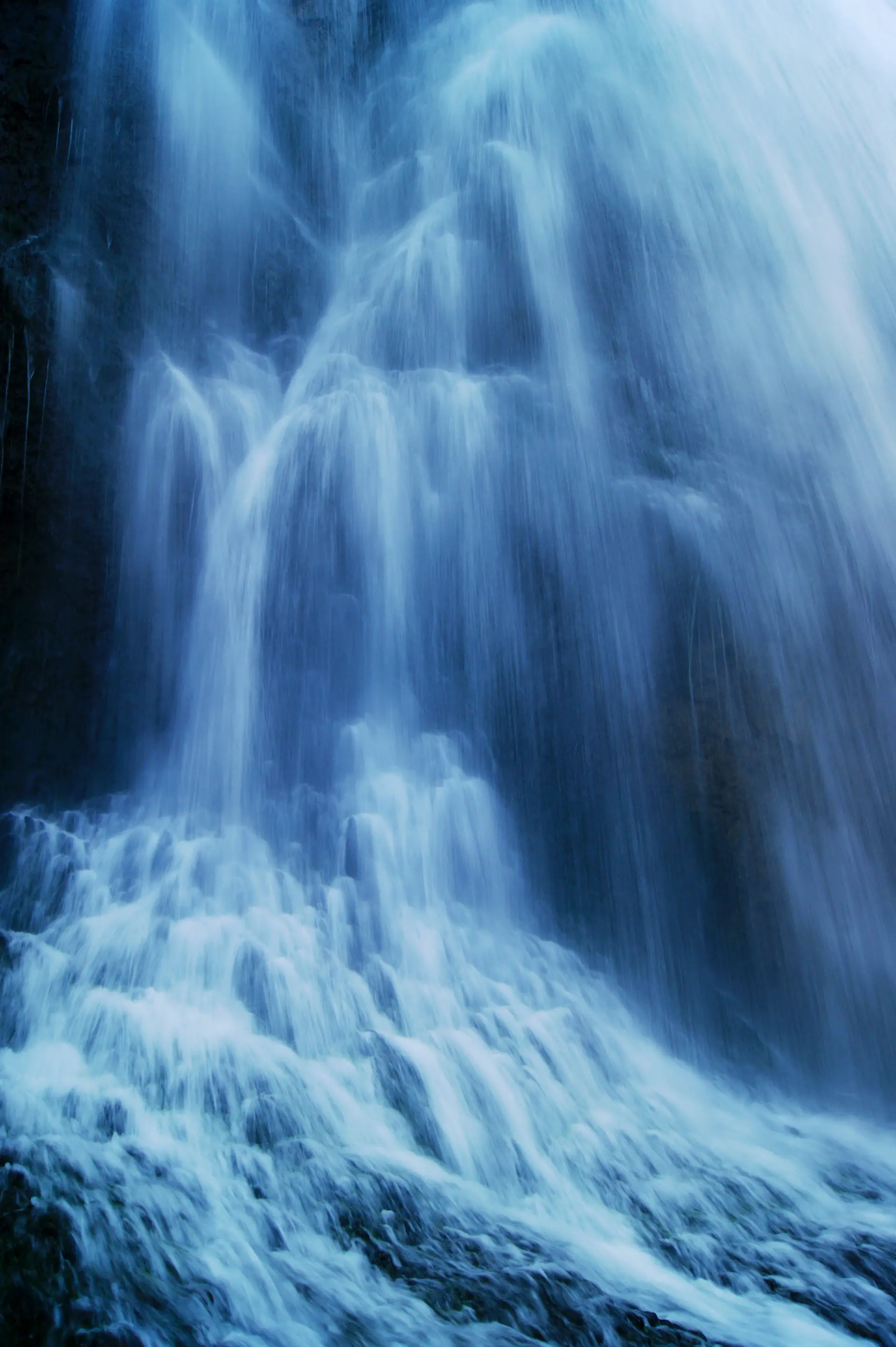 A partly frozen waterfall glowing in cold blue light