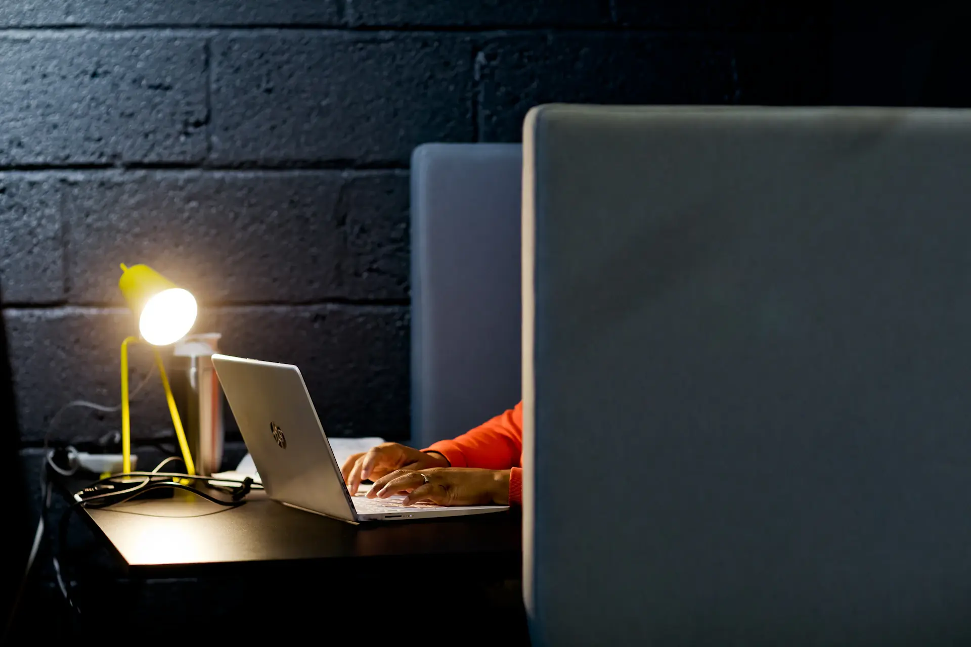 A designer at a softly lit desk, mid-thought, in front of a laptop