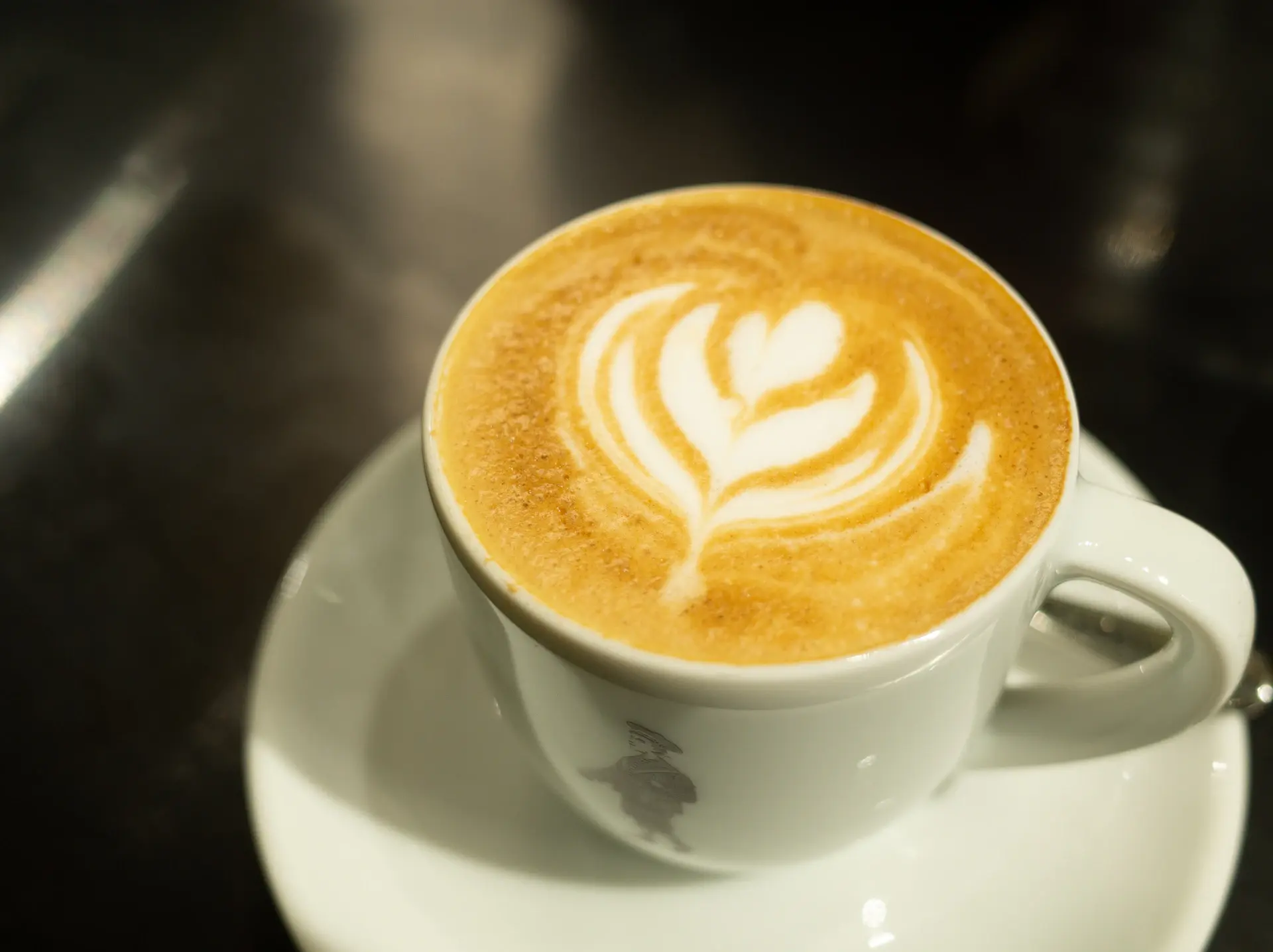 Barista pouring tulip latte art into a ceramic cup