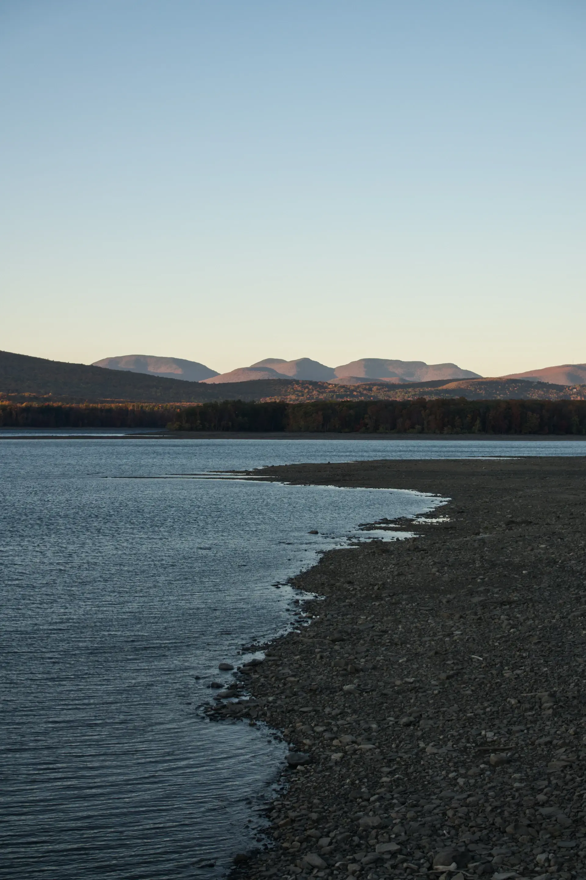 Empty lakeshore at dusk under soft amber light