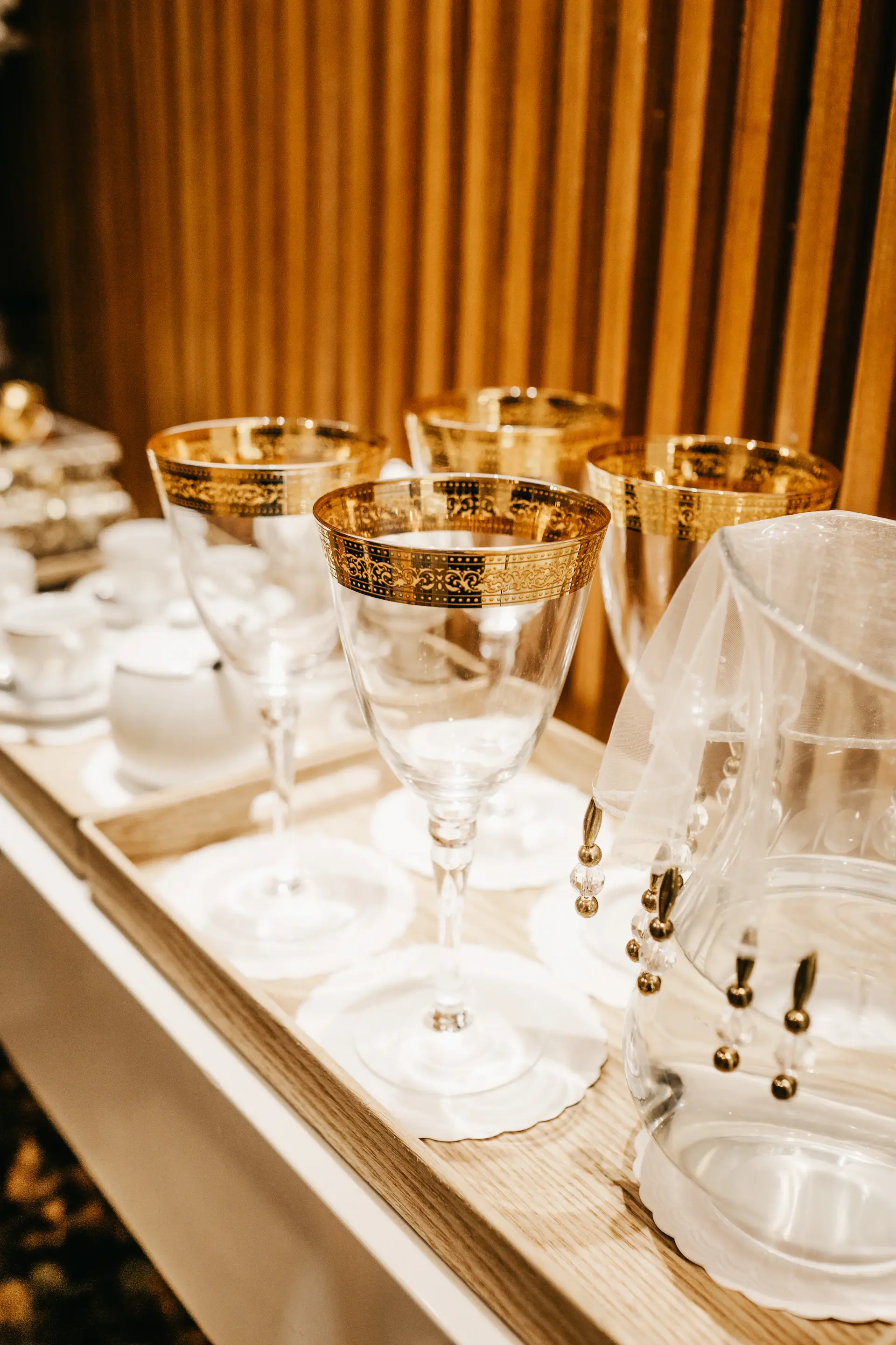 Close detail of gold-rimmed glassware and ivory florals
