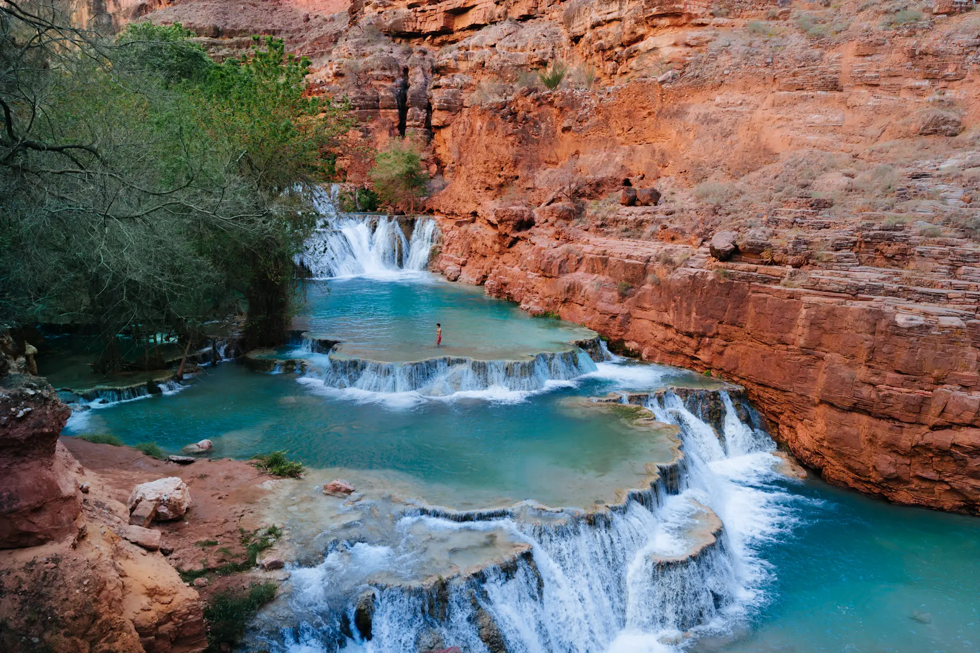 Waterfall pouring into a deep blue canyon pool