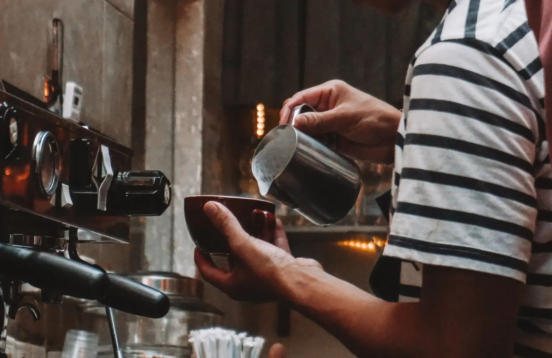 Barista pouring milk over espresso