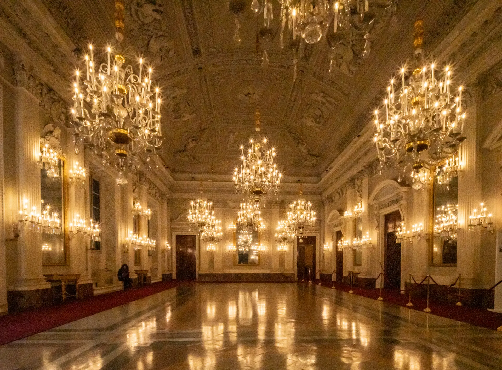 Isabella and Alexander beneath a gilded chandelier in the Grand Ballroom