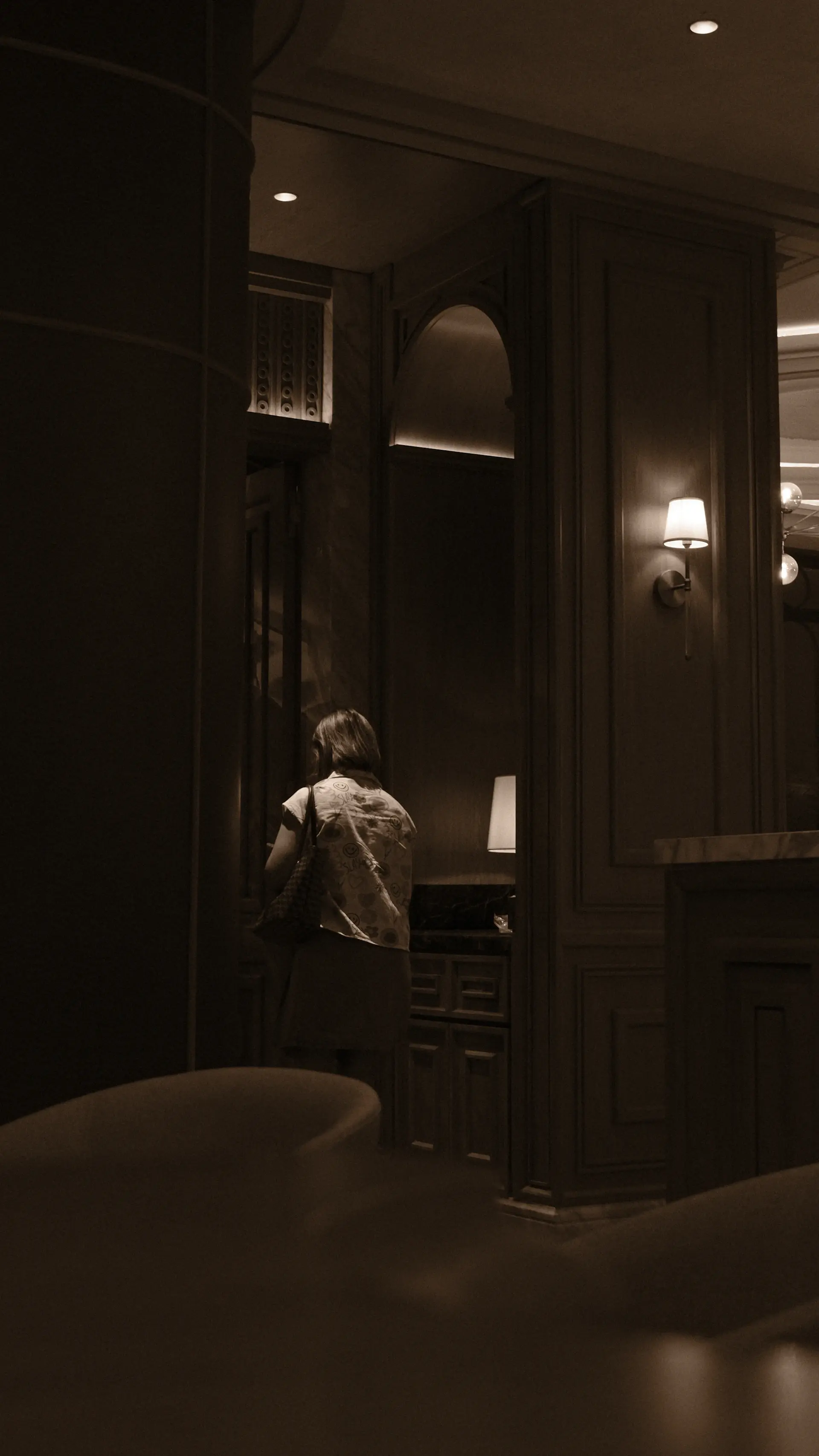 Poised concierge in refined attire, softly lit against a dark interior