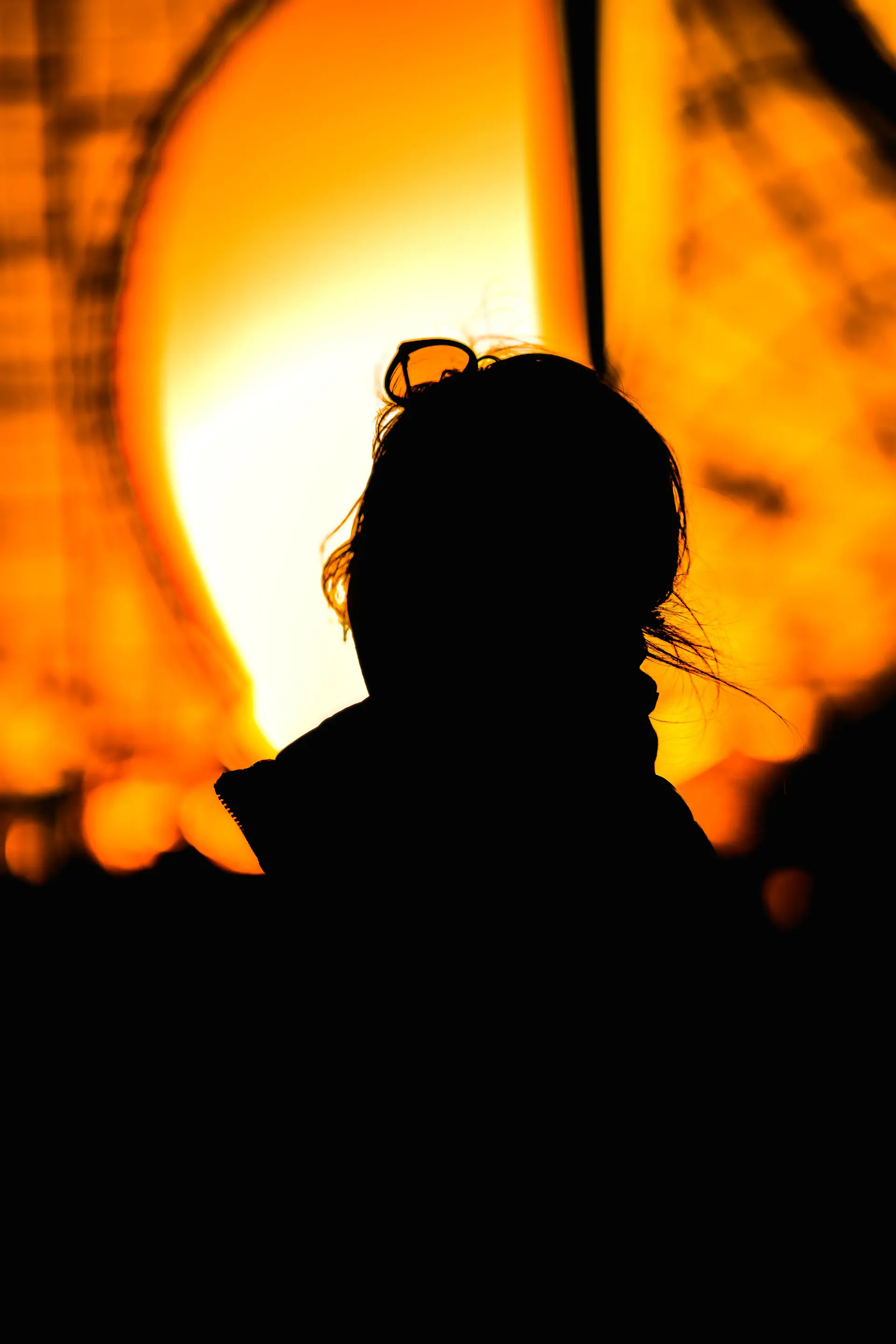 Silhouette phụ nữ cầm chiếc ly, đứng nghiêng bên lò sưởi