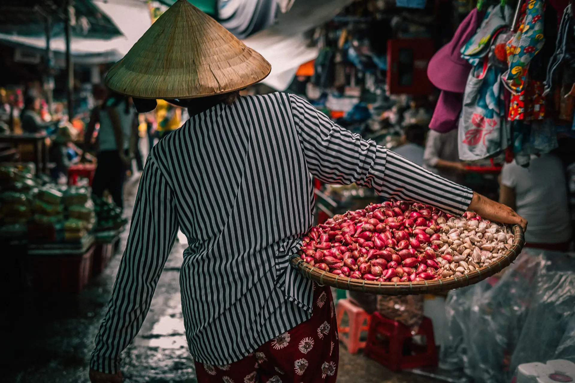 Người phụ nữ sắp xếp rau củ trên sạp hàng nhỏ trong chợ truyền thống buổi sáng sớm